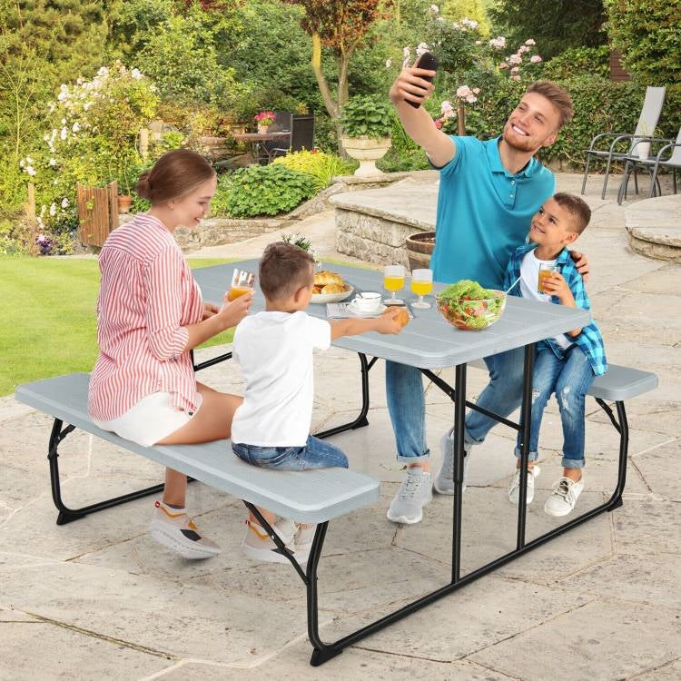 Grey folding picnic table with two attached benches, ideal for outdoor patio dining and portable outdoor furniture.