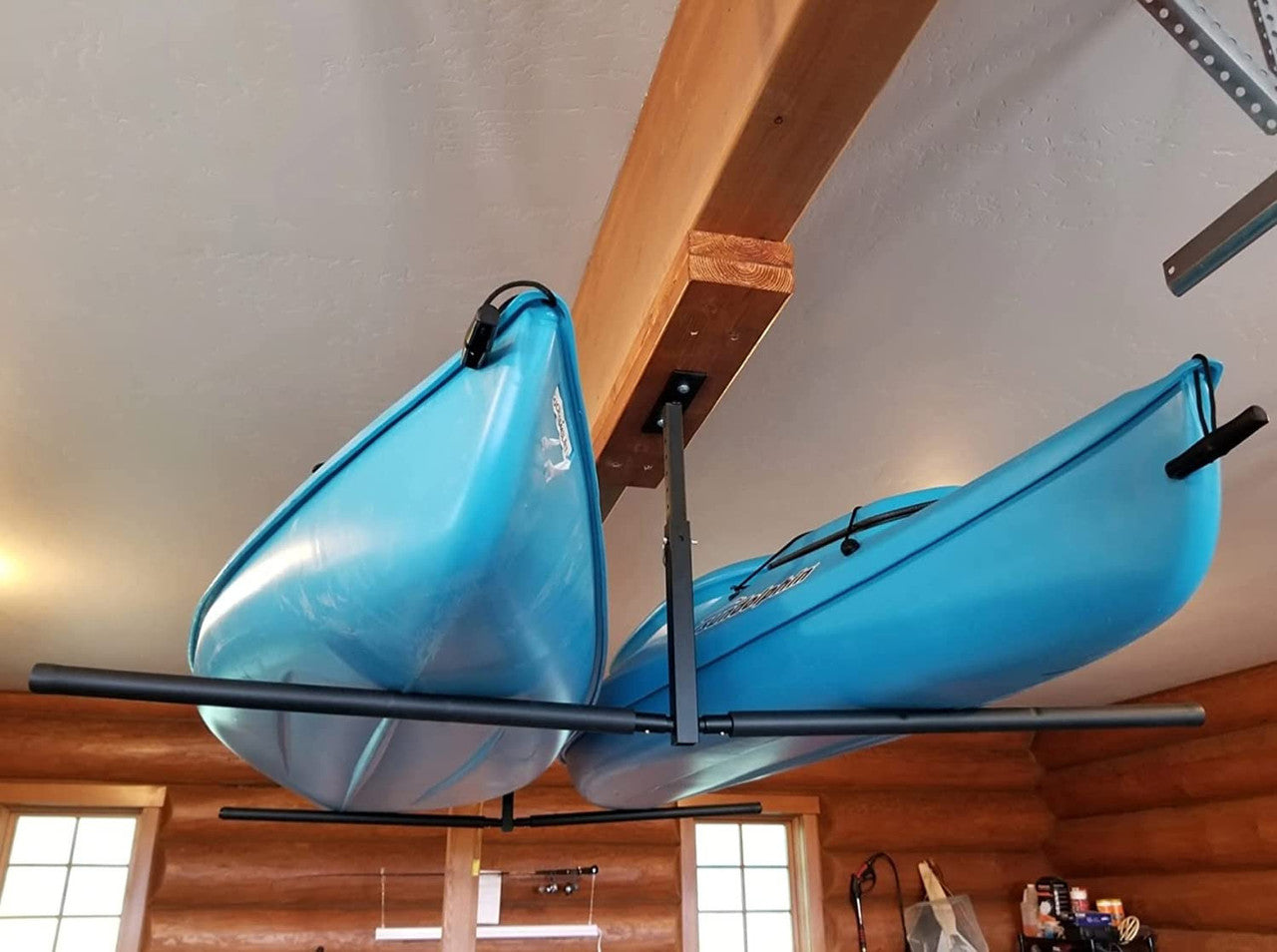 Two blue kayaks hanging from a ceiling rack in a garage.