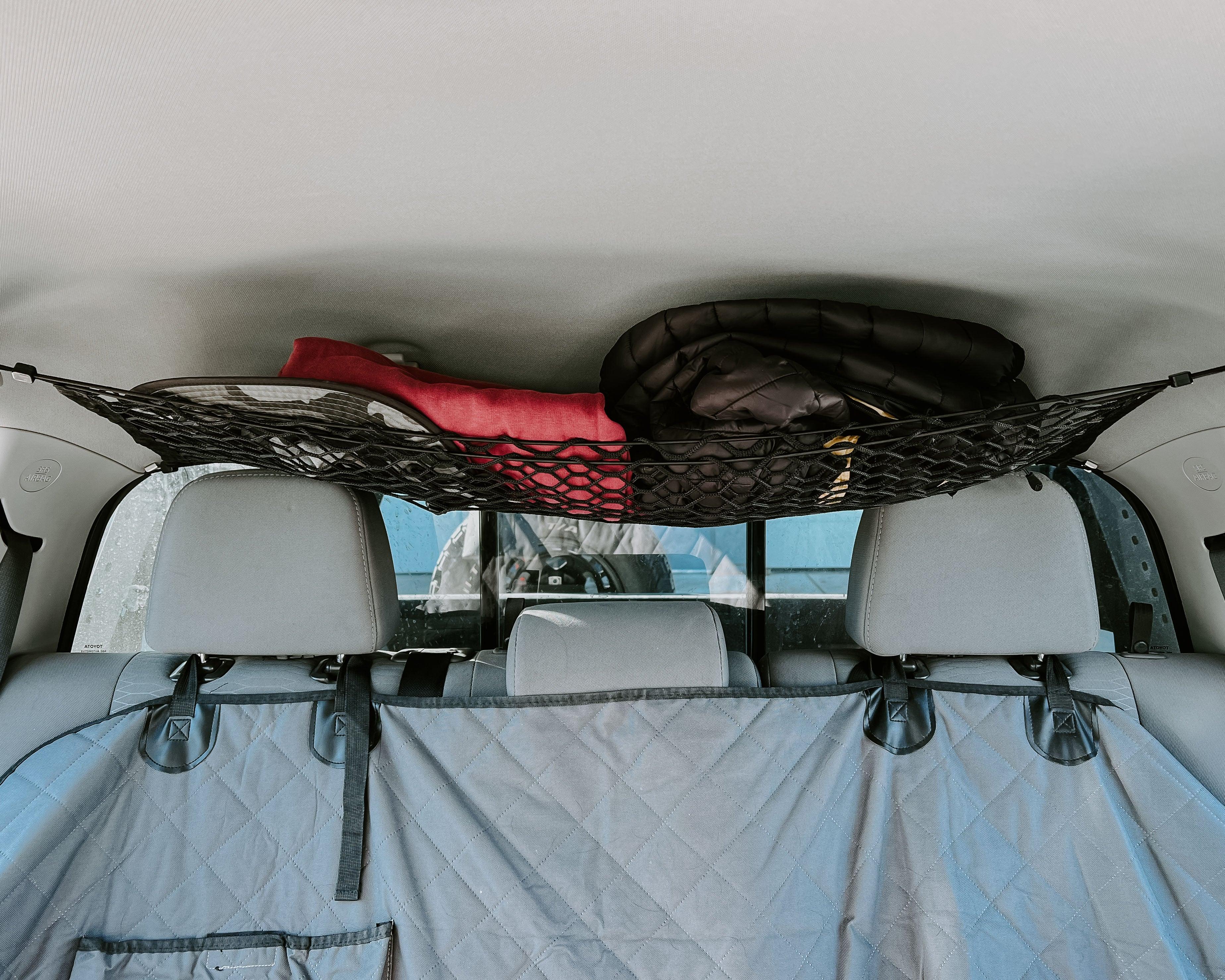 Toyota Tacoma attic storage net by Flatirons Overland, shown securing items in the truck's attic space for organization.