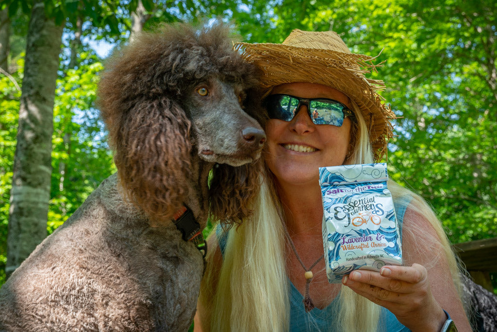 Lavender and arnica bath salts in a jar, natural salt for the tub by Essential Journeys, with lavender flowers and arnica herbs.