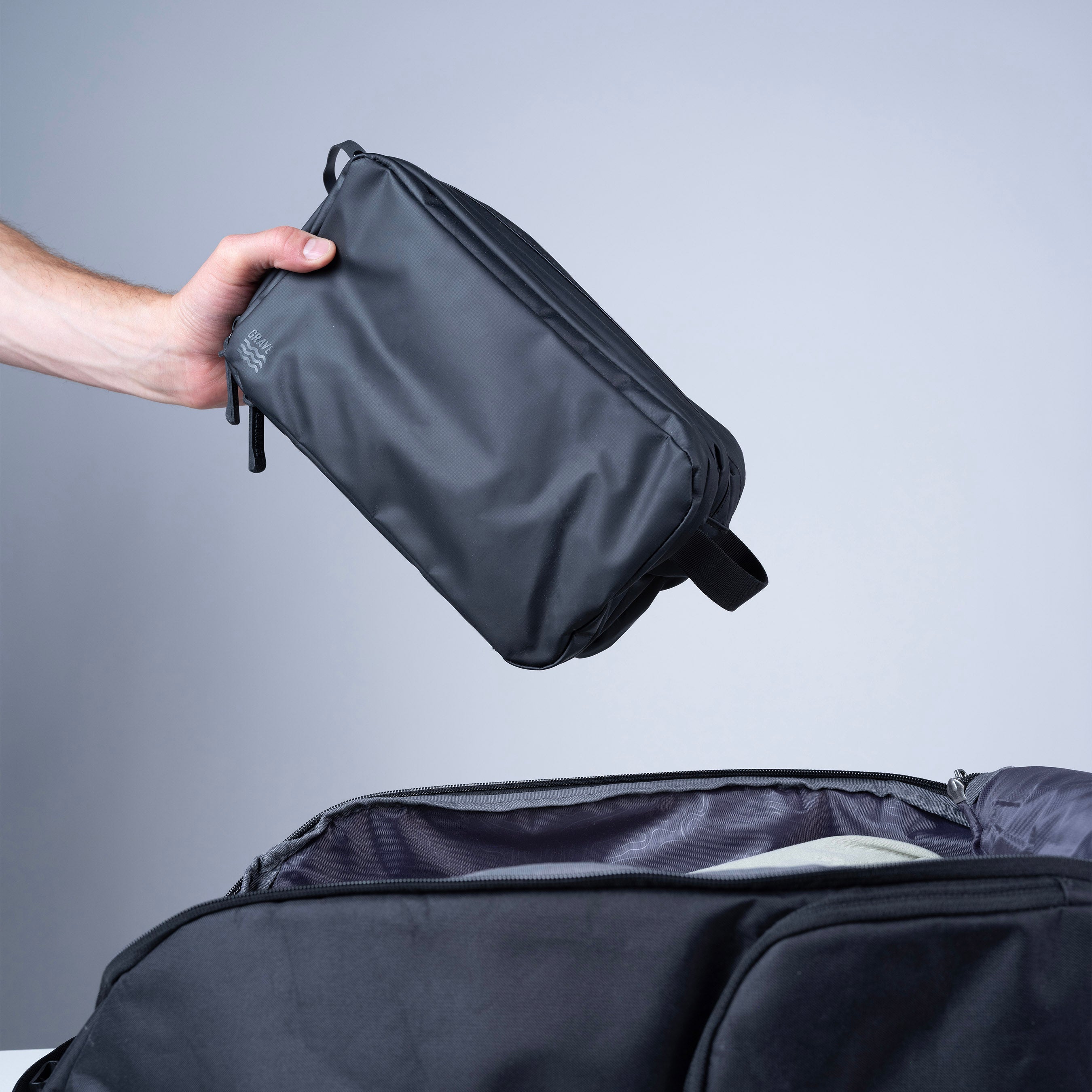 Gravel Max™ Toiletry Bag showing a compact, black toiletry bag with zipper closure and multiple compartments for travel essentials.