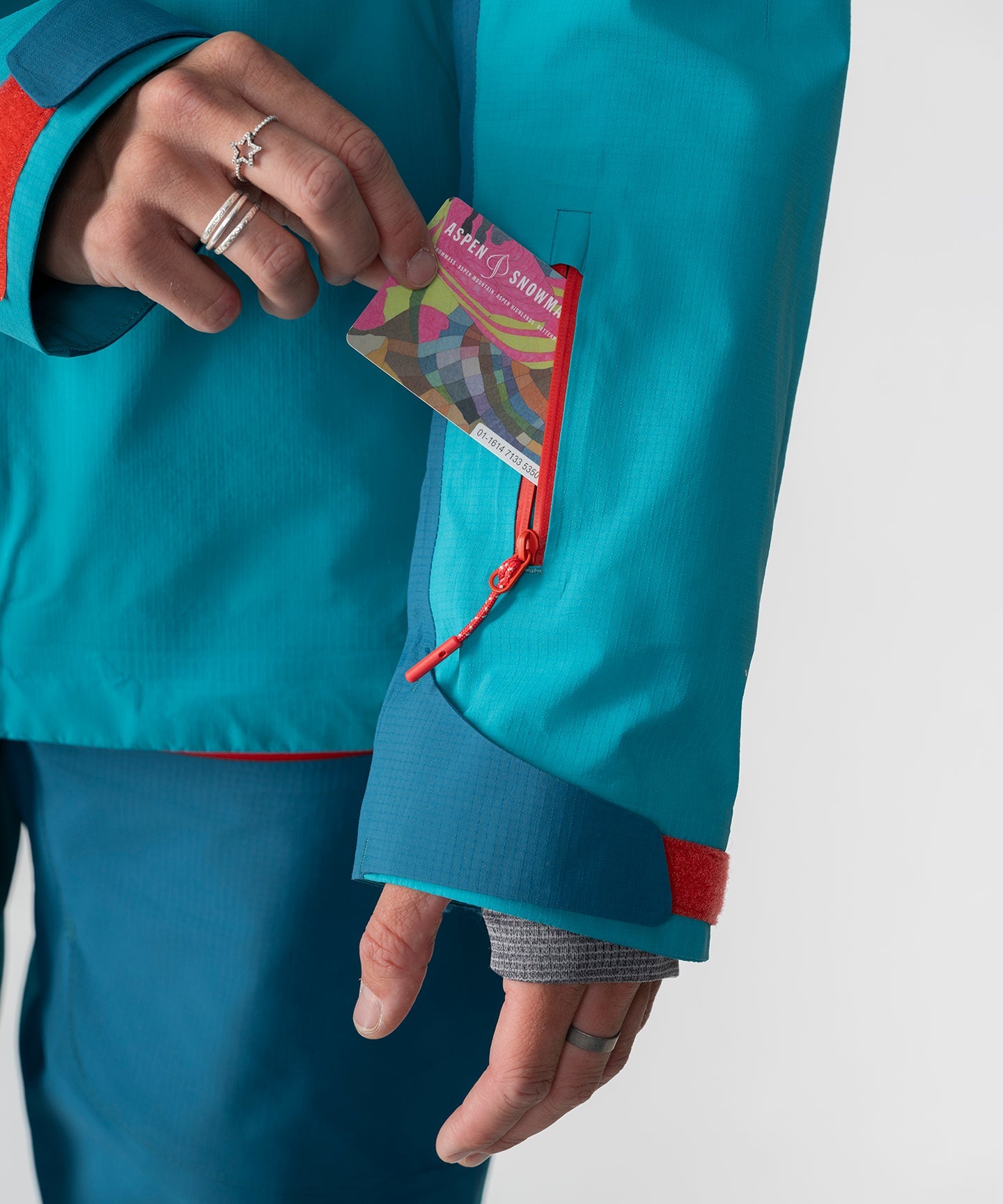 Dark teal Strafe Outerwear Meadow 3L shell jacket displayed with a hood and adjustable cuffs in an outdoor setting.