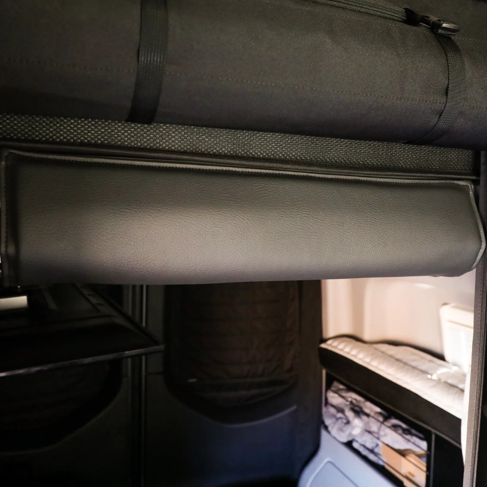 Canyon Adventure Vans CAV branded bed head bumper for 2019+ REVEL van, shown installed on vehicle interior in black fabric.