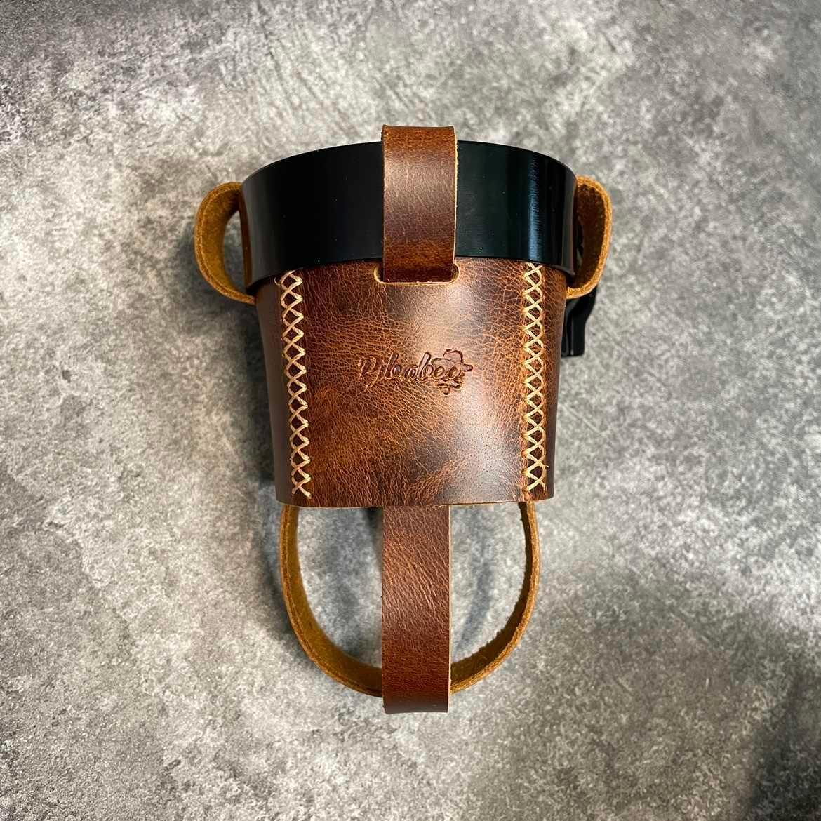 Handmade leather motorcycle water bottle holder from Bean's Moto Booth, designed to attach securely to motorcycle accessories.