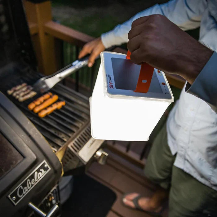 Alpenglow PackLite Titan 2-in-1 Power Lantern illuminating a grill outdoors at night, showcasing its white LED light.