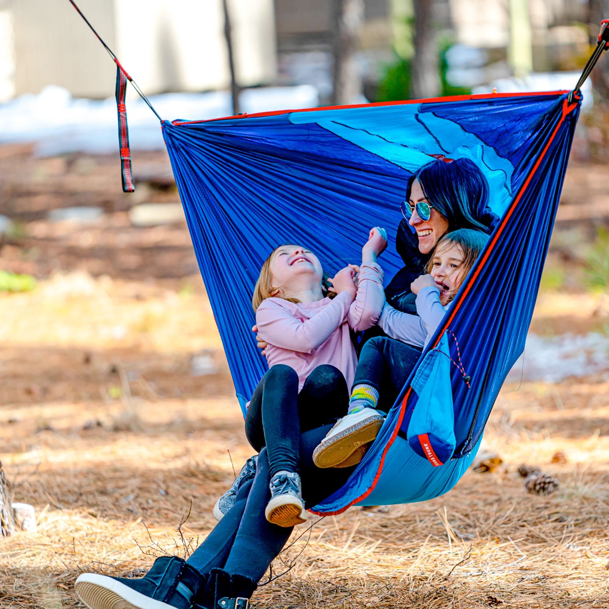 GrandTrunk ROVR™ Hanging Chair in a vibrant design, suspended from a sturdy tree branch in an outdoor setting.