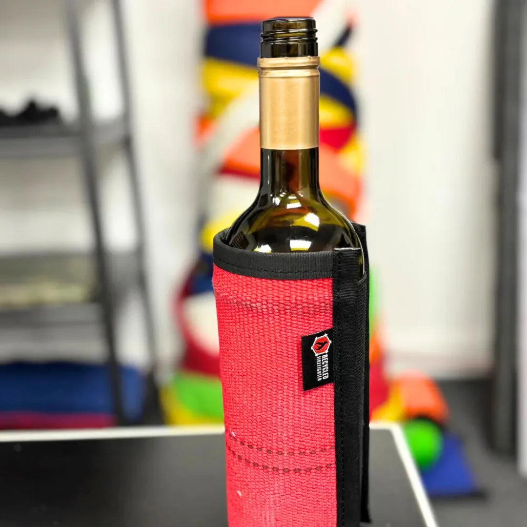 Recycled Firefighter firehose wine bottle cover in bright red with black accents, designed to resemble a firefighter's hose.