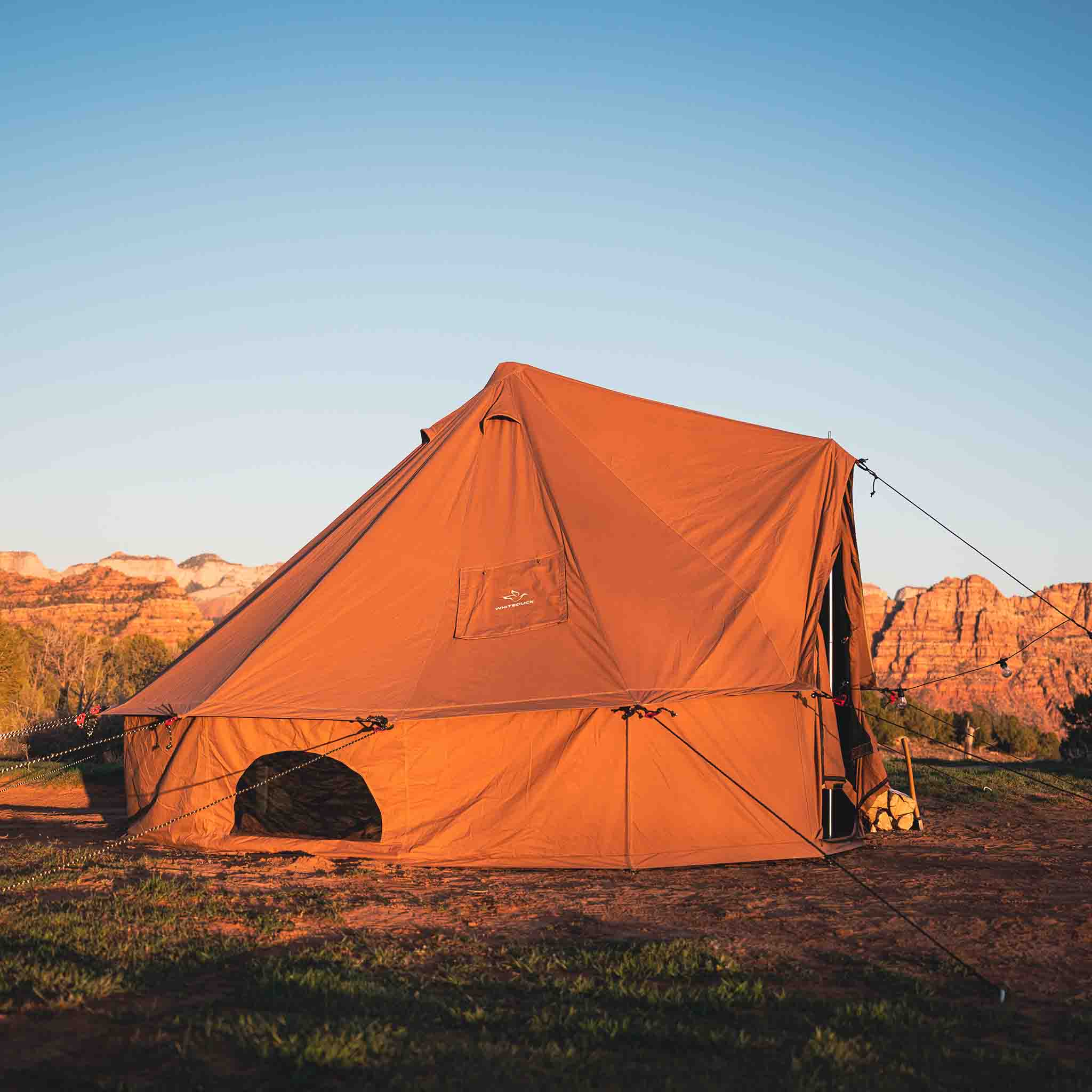 Desert red Regatta Bell Tent by White Duck Outdoors set up in sunlight, showcasing its spacious, traditional design and durable fabric.