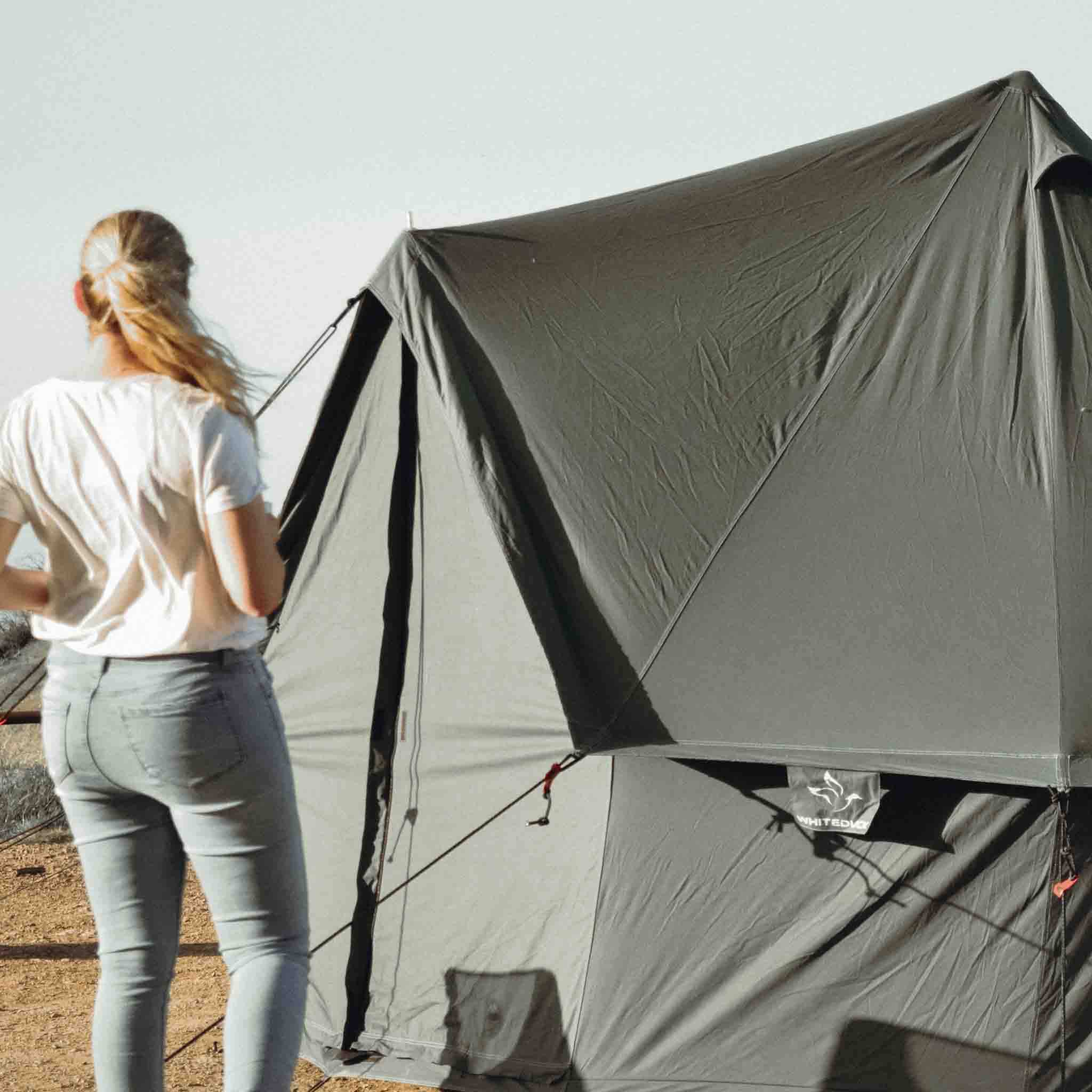 Forest green Regatta Bell Tent by White Duck Outdoors with a girl standing in front of the tent in a natural outdoor setting.