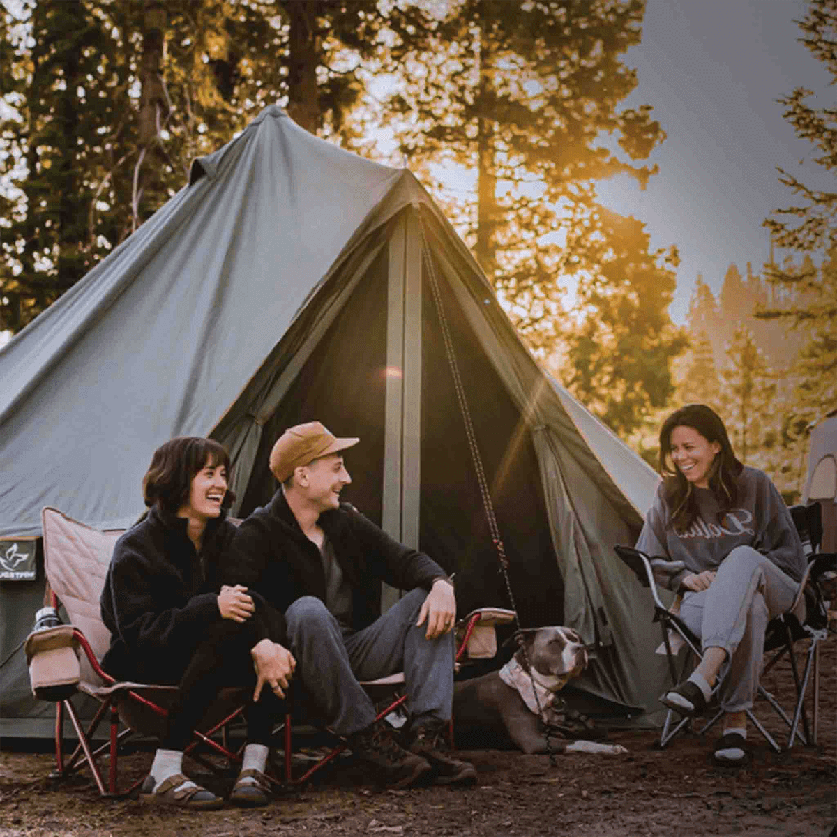 Forest green 20-foot Regatta Bell Tent by White Duck Outdoors with people sitting in front in a wooded setting.