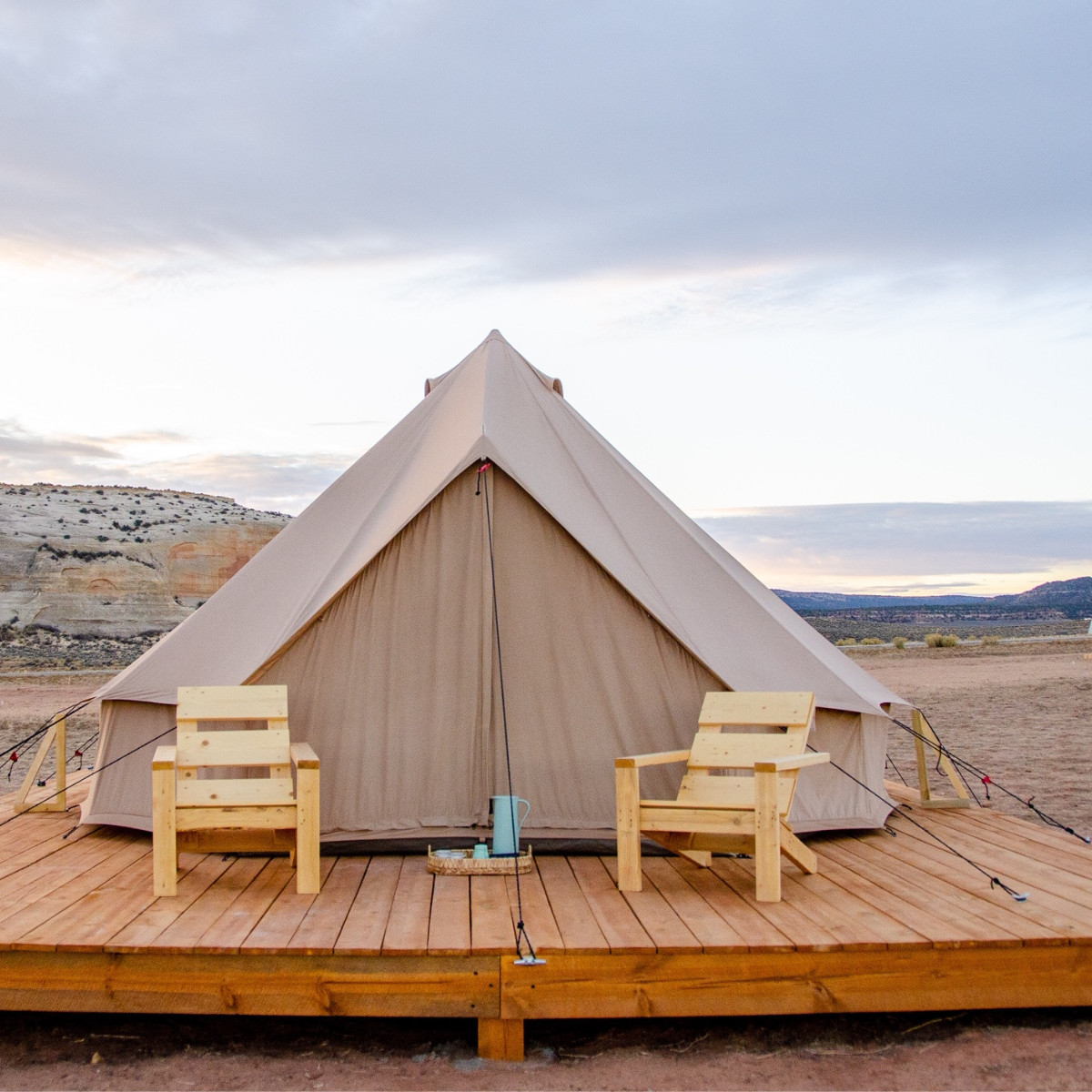 Sandstone beige Regatta Bell Tent by White Duck Outdoors set up on a platform with chairs outdoors.