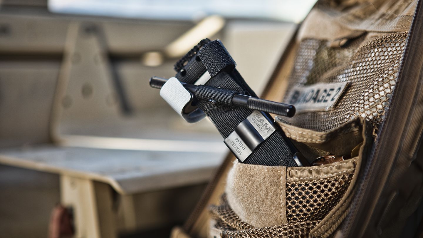 Black and blue SAM XT Extremity Tourniquet for bleeding management, shown with straps and locking mechanism.