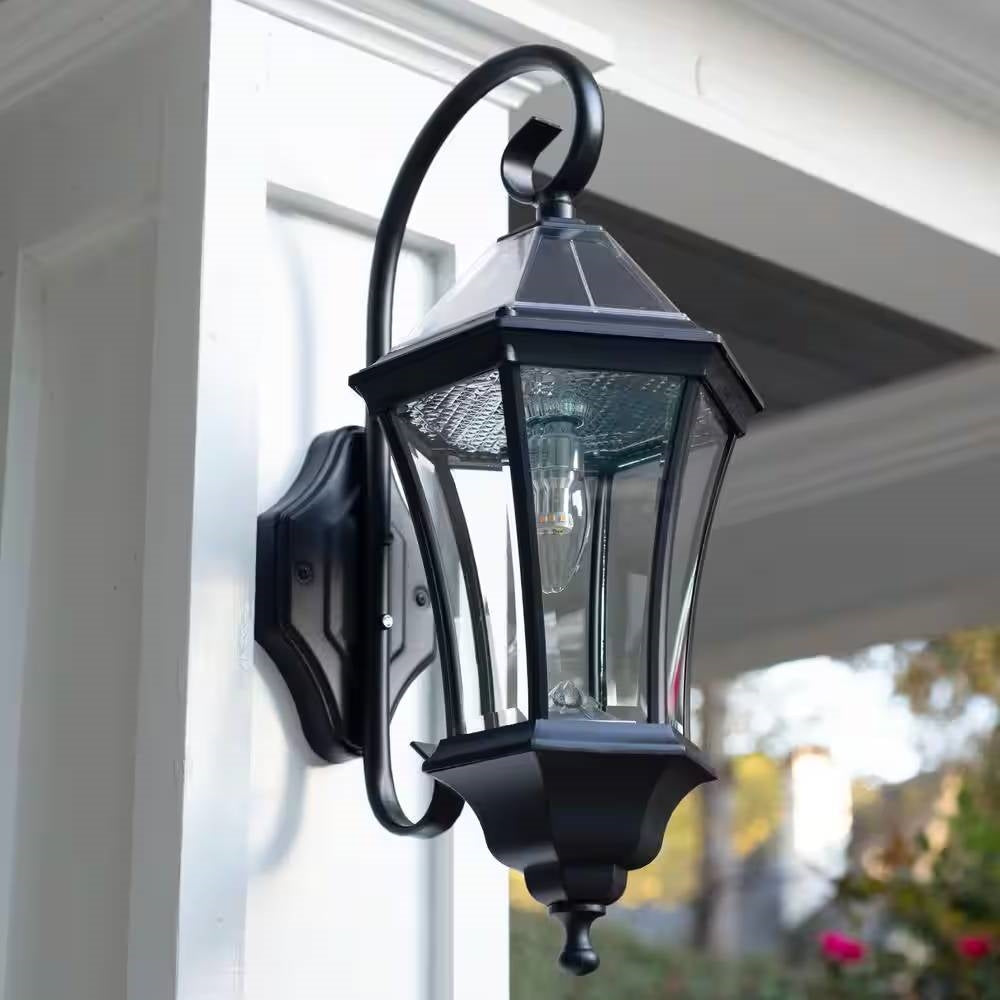 Black outdoor farmhouse solar wall light by HomePacific with 150 lumens, mounted on a wall in a rustic outdoor setting.