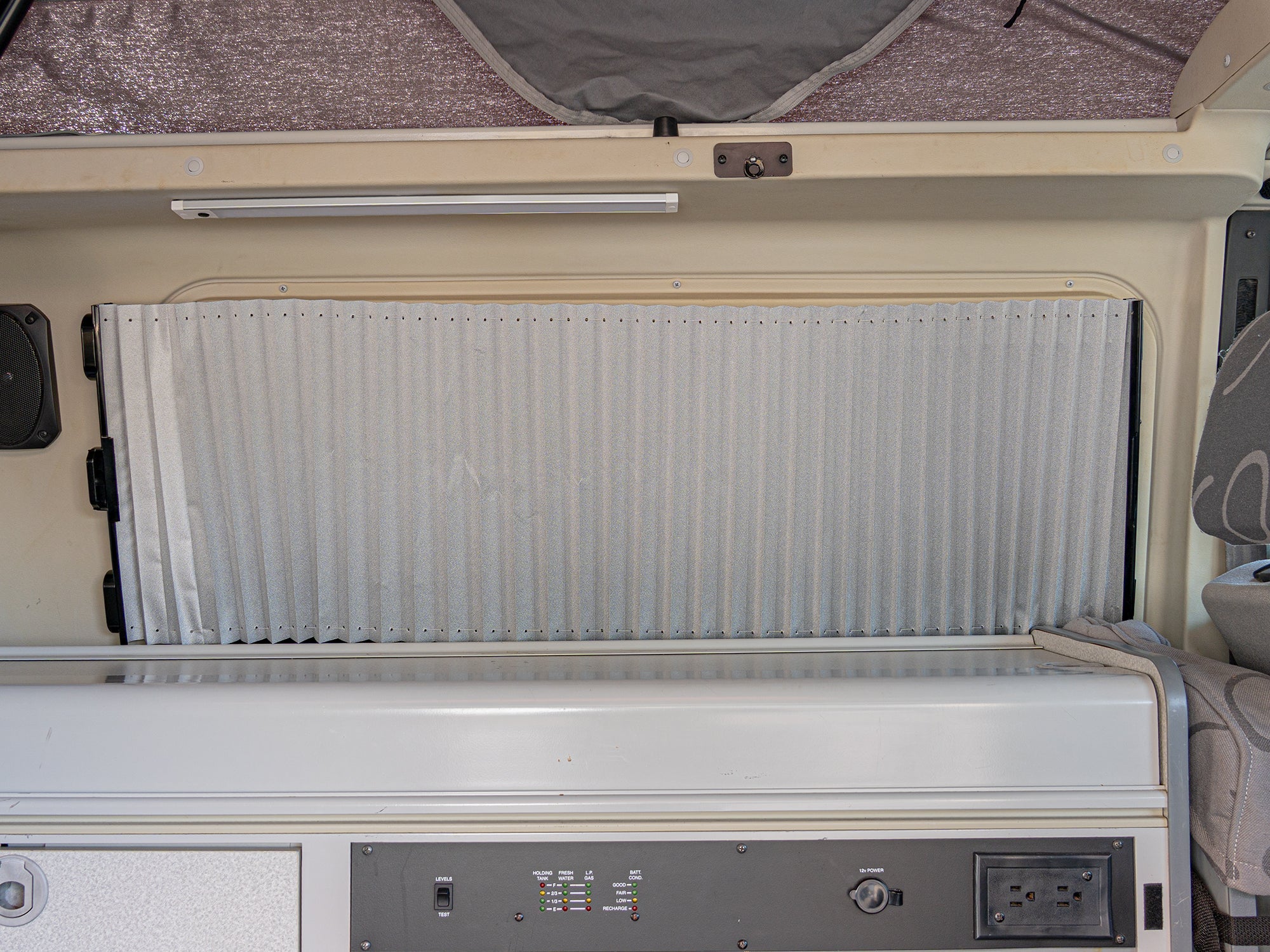 Open retracting sun and privacy shade by GoWesty in a vanagon or Eurovan galley, providing shade and privacy for the vehicle interior.