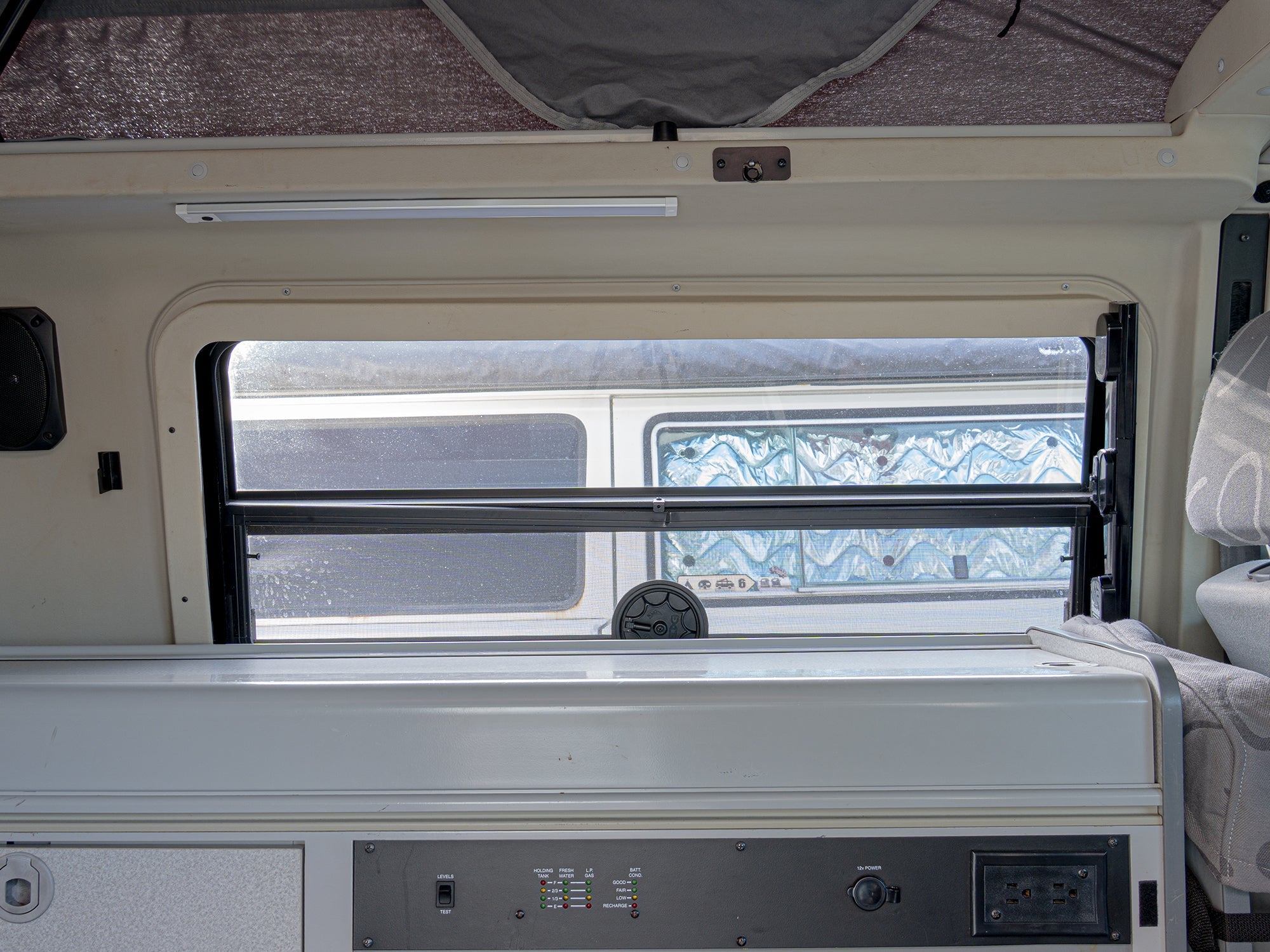GoWesty retractable sun and privacy shade installed in a Bus/Vanagon/Eurovan galley area, shown in retracted position.