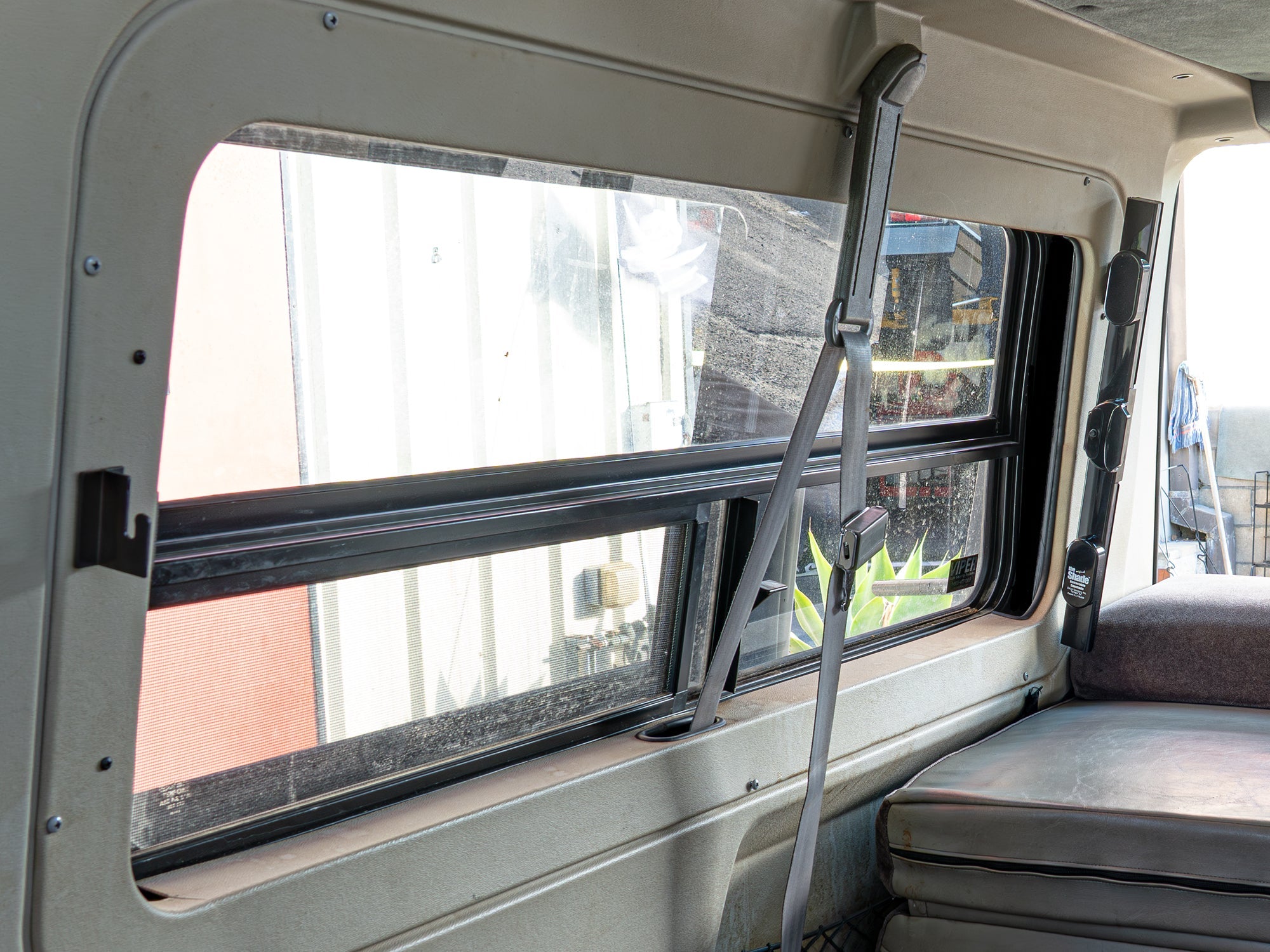 GoWesty retracting sun and privacy shade installed in the right rear window of a Vanagon or Eurovan, partially retracted.