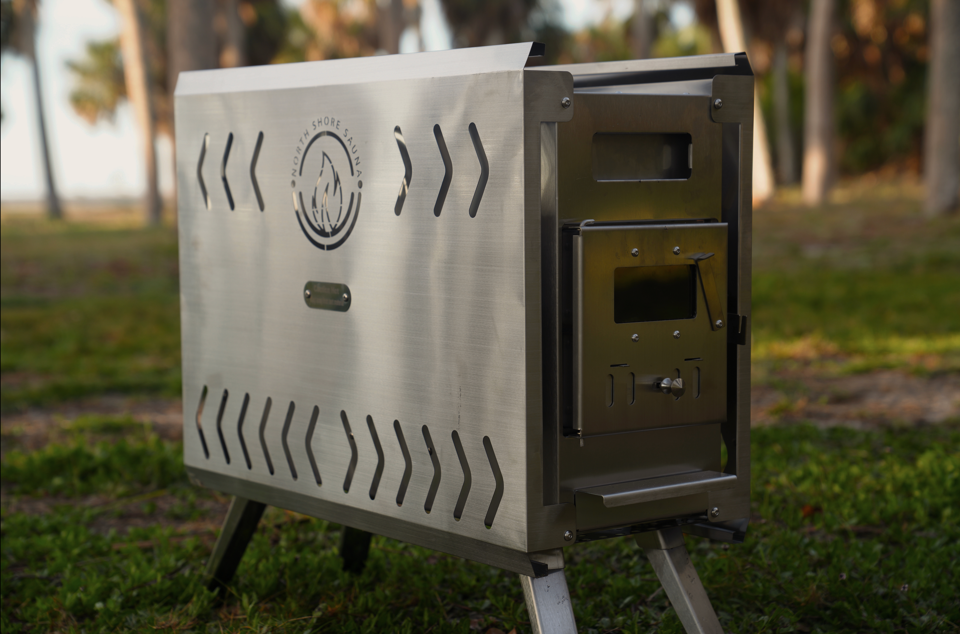 Portable North Shore Sauna tent wood stove in brushed stainless steel, showcasing its compact design and heating elements.