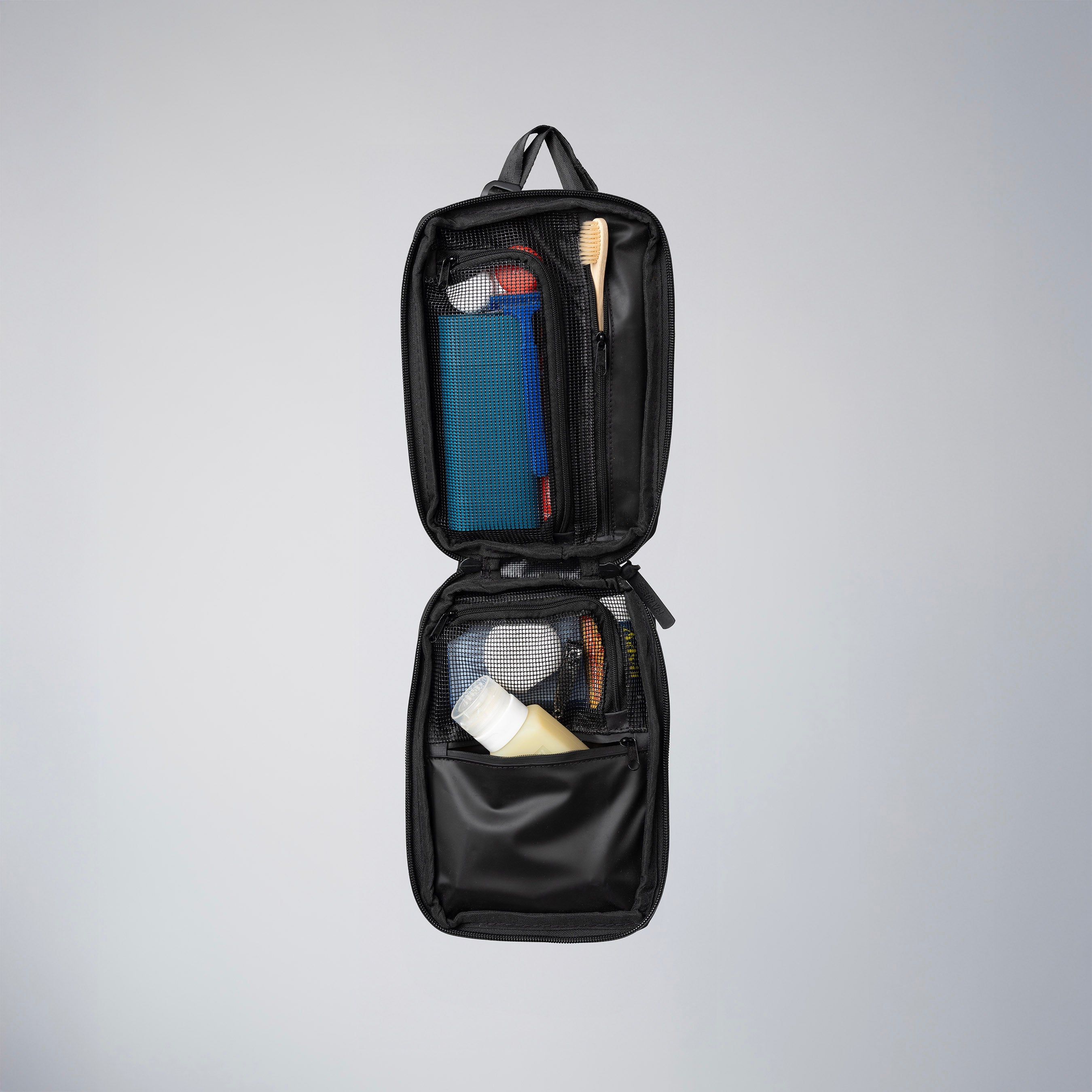 Open Gravel Slim™ Toiletry Bag showing compartments and interior organization for travel toiletries.