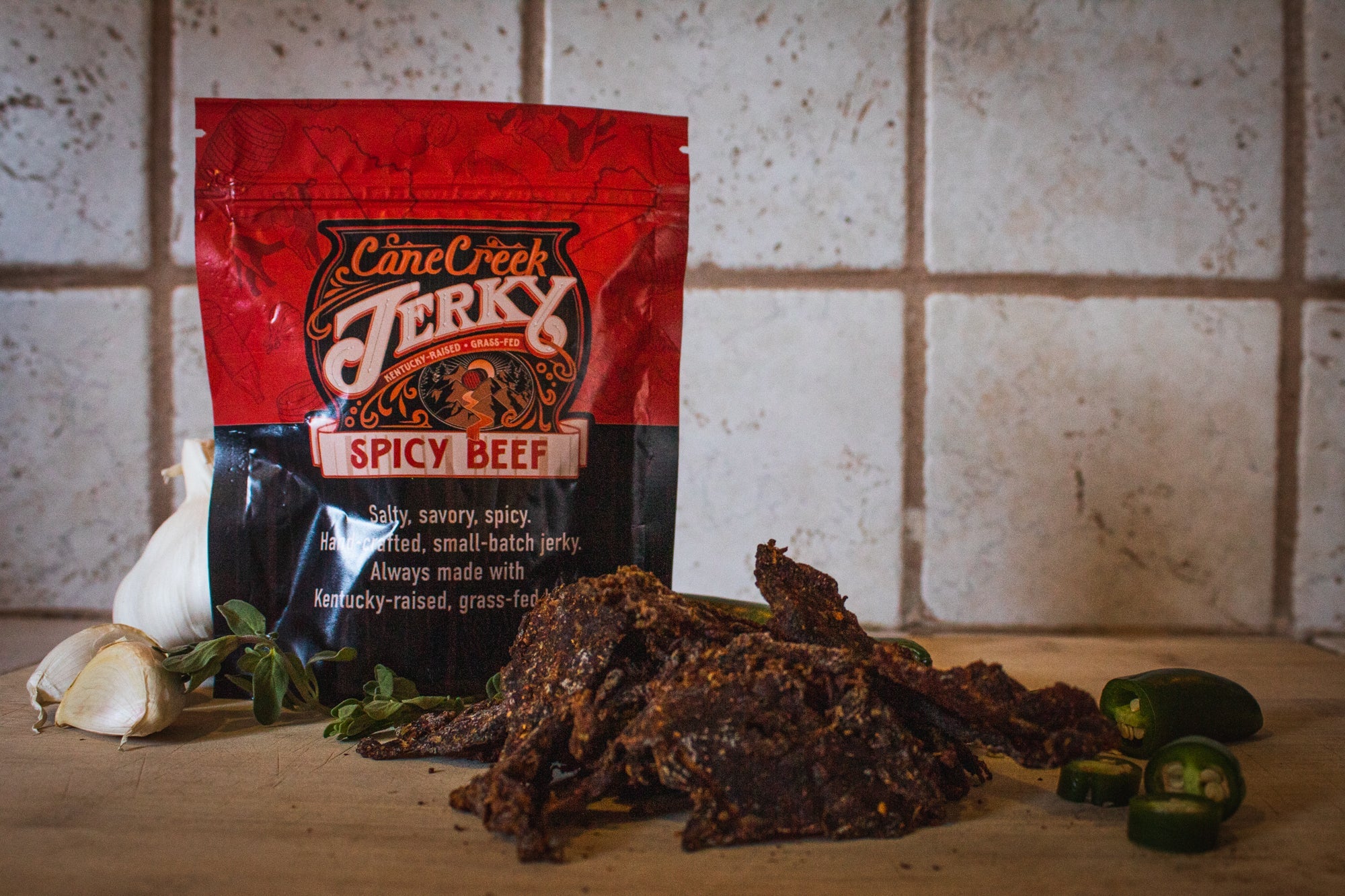 Spicy beef jerky by Cane Creek Jerky, showing strips of flavorful, seasoned dried beef with a spicy glaze on a neutral background.