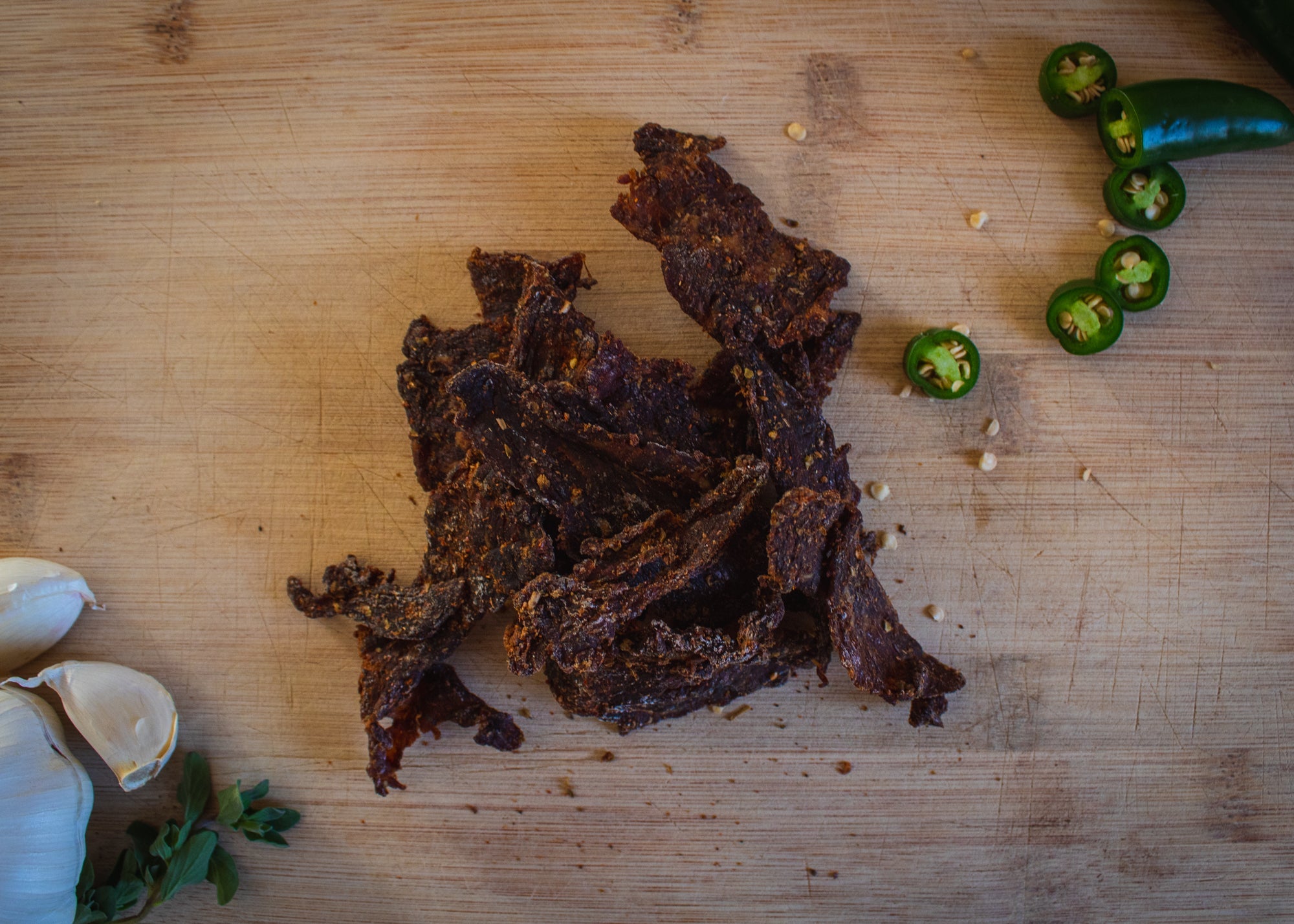 Spicy beef jerky by Cane Creek Jerky, showing a close-up of seasoned, dried beef strips with a spicy glaze.