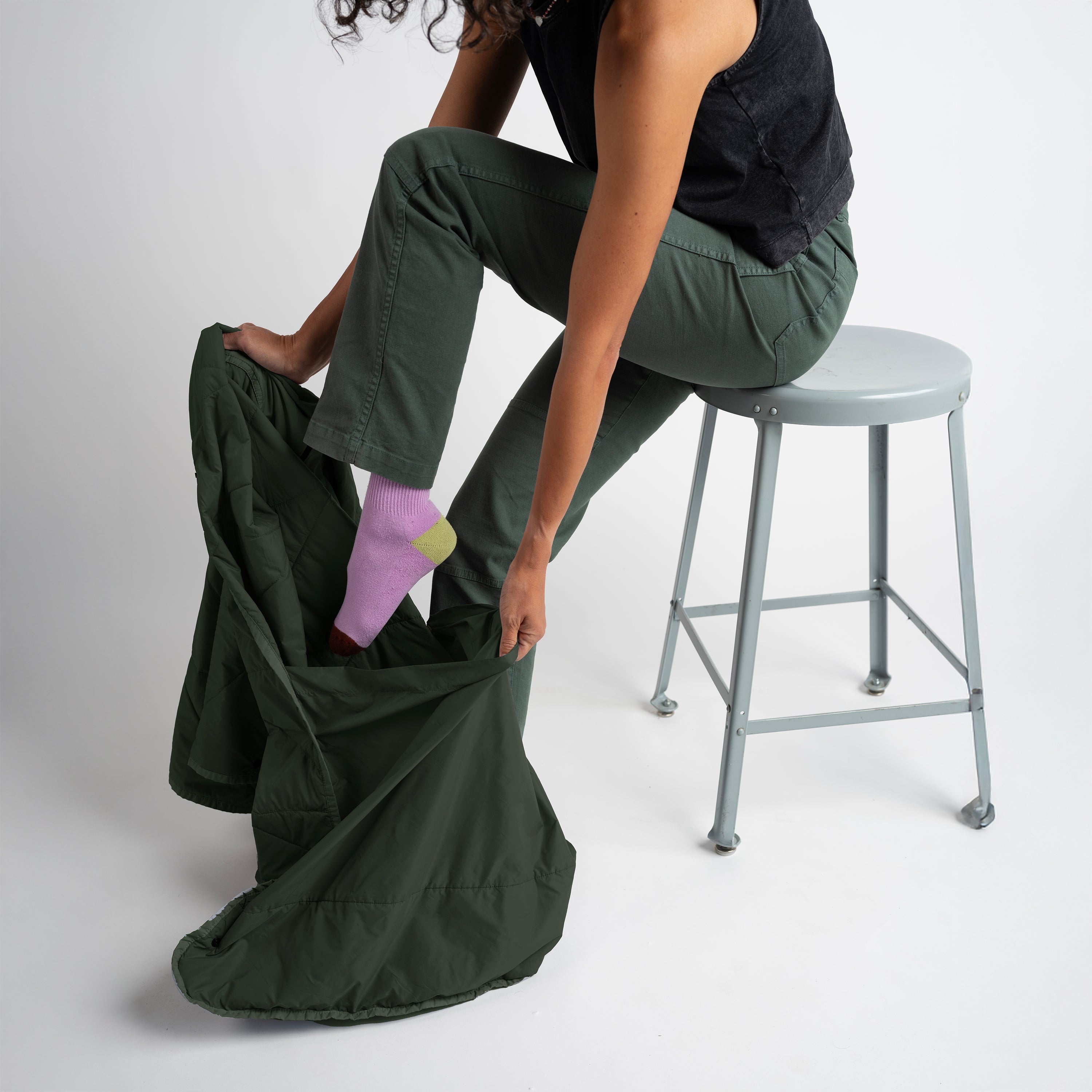 Gravel Layover™ travel blanket in spruce color, soft fabric with folded edges, suitable for outdoor or travel use.
