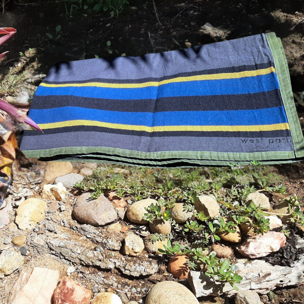 West Path waxed canvas camping blanket spread out outdoors, showing its durable, weather-resistant throw blanket design for camping and bushcraft.