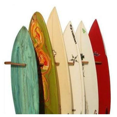 Cor Surf bamboo triple surfboard wall rack holding three surfboards and skateboards in a modern home setting.