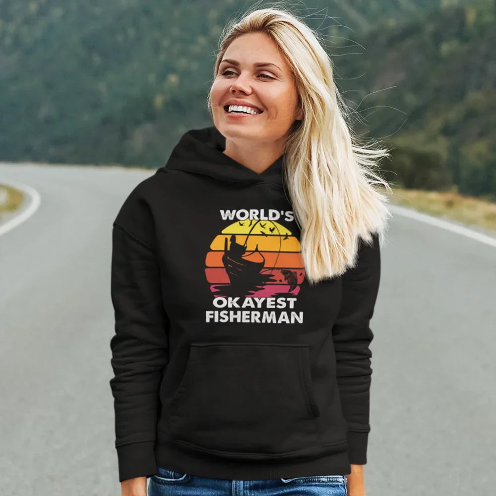 Black unisex hoodie featuring the "World's Okayest Fisherman" logo by Outdoorzees, worn by a female model.