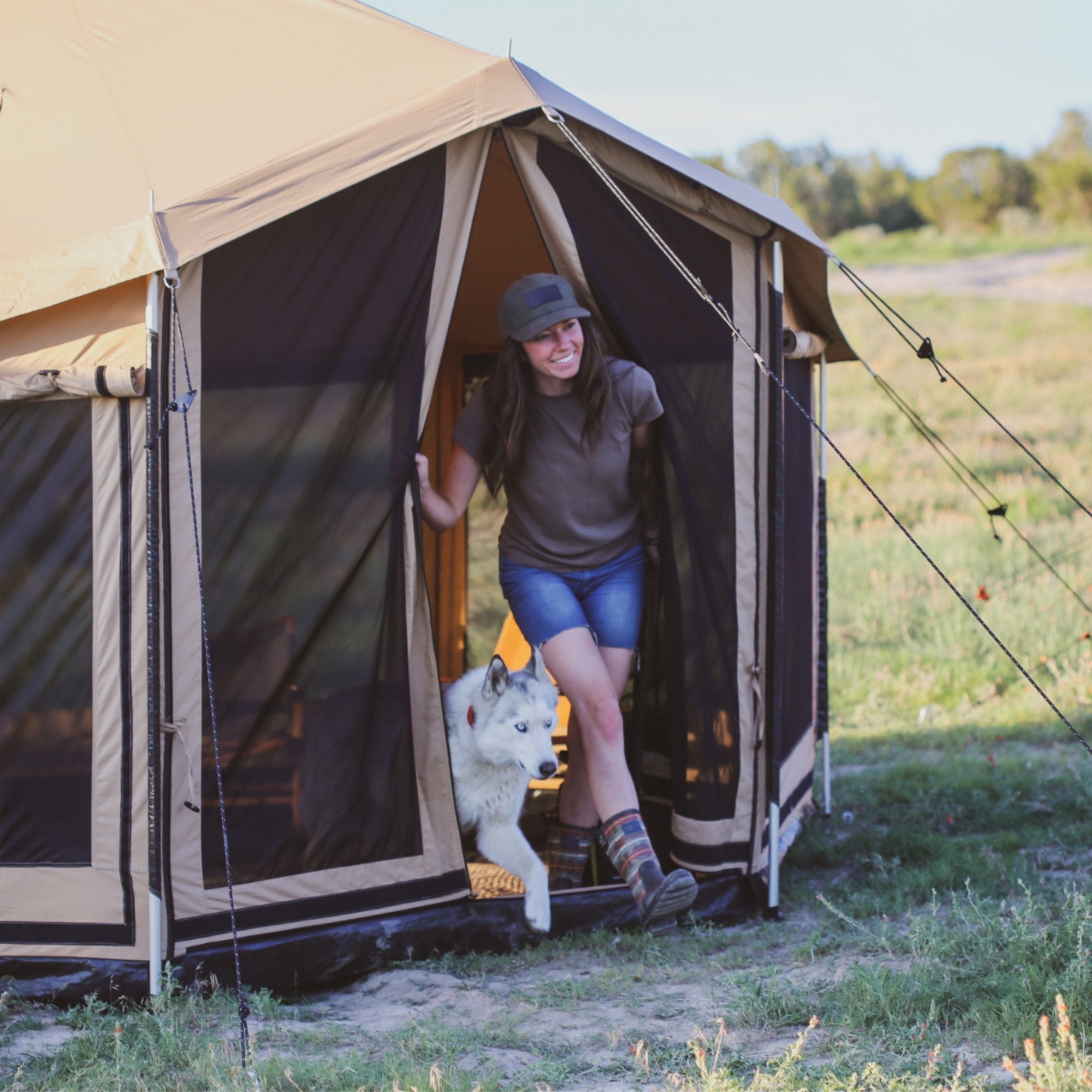 Altimus Bell Tent by White Duck Outdoors set up in grasslands with a woman and her dog outside.