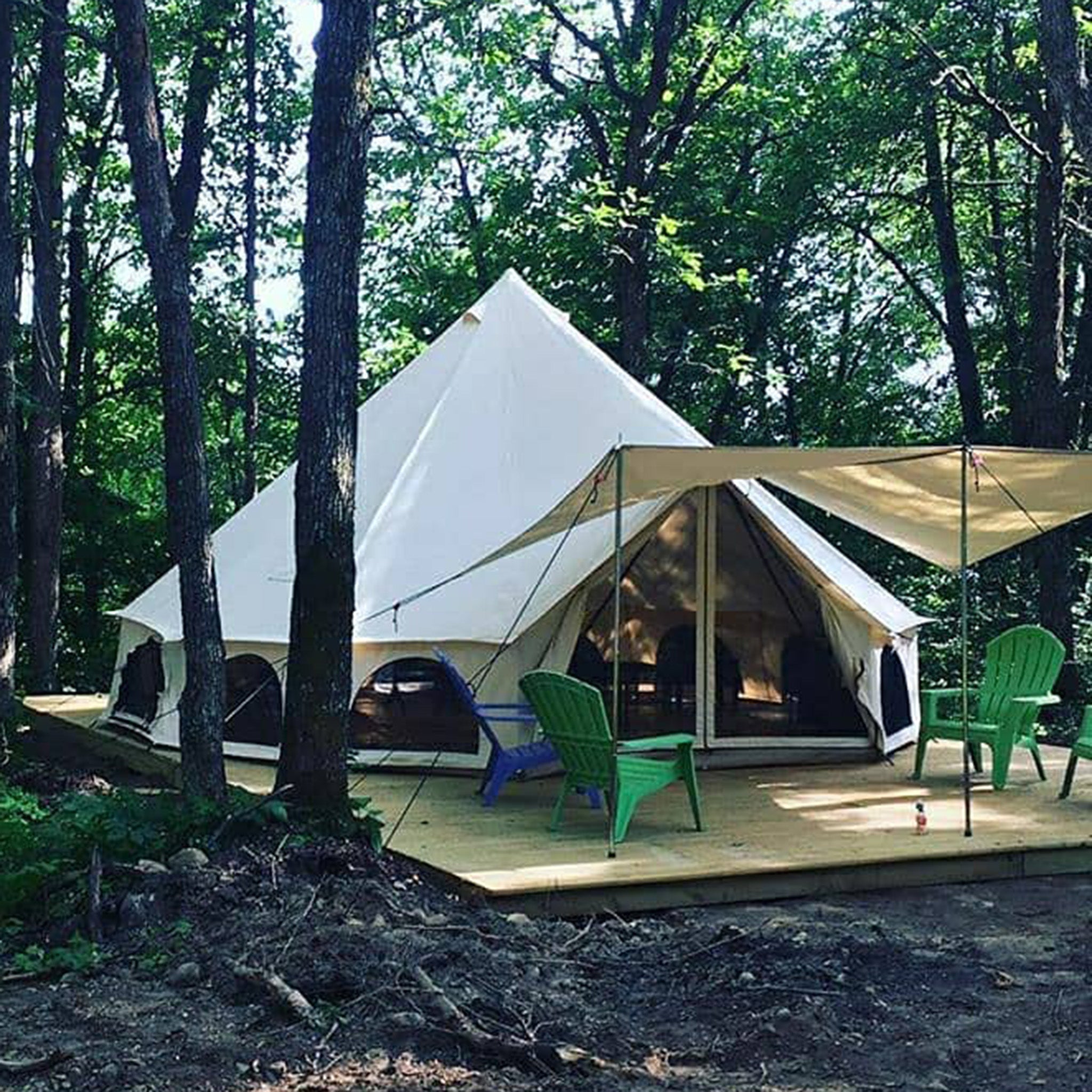 White Duck Outdoors Avalon bell tent awning set in a forest, providing extra shaded outdoor space and shelter.