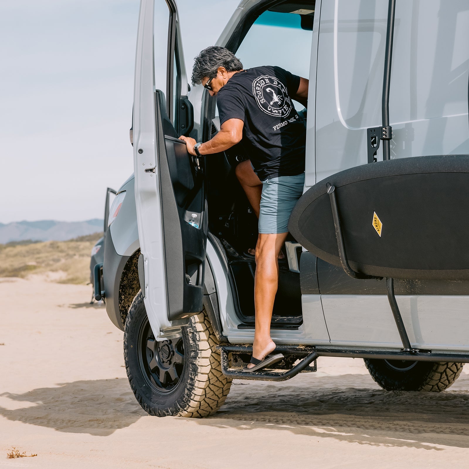 Vanspeed Sprinter side steps installed on a van parked at the beach, showcasing durable exterior design and functionality.