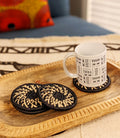 Set of four handmade woven drink coasters in multiple colors by Reflektion Design, featuring black woven material and stylish accents.