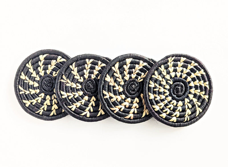 Set of four handmade woven drink coasters by Reflektion Design in black, white, and natural raffia, boho style.