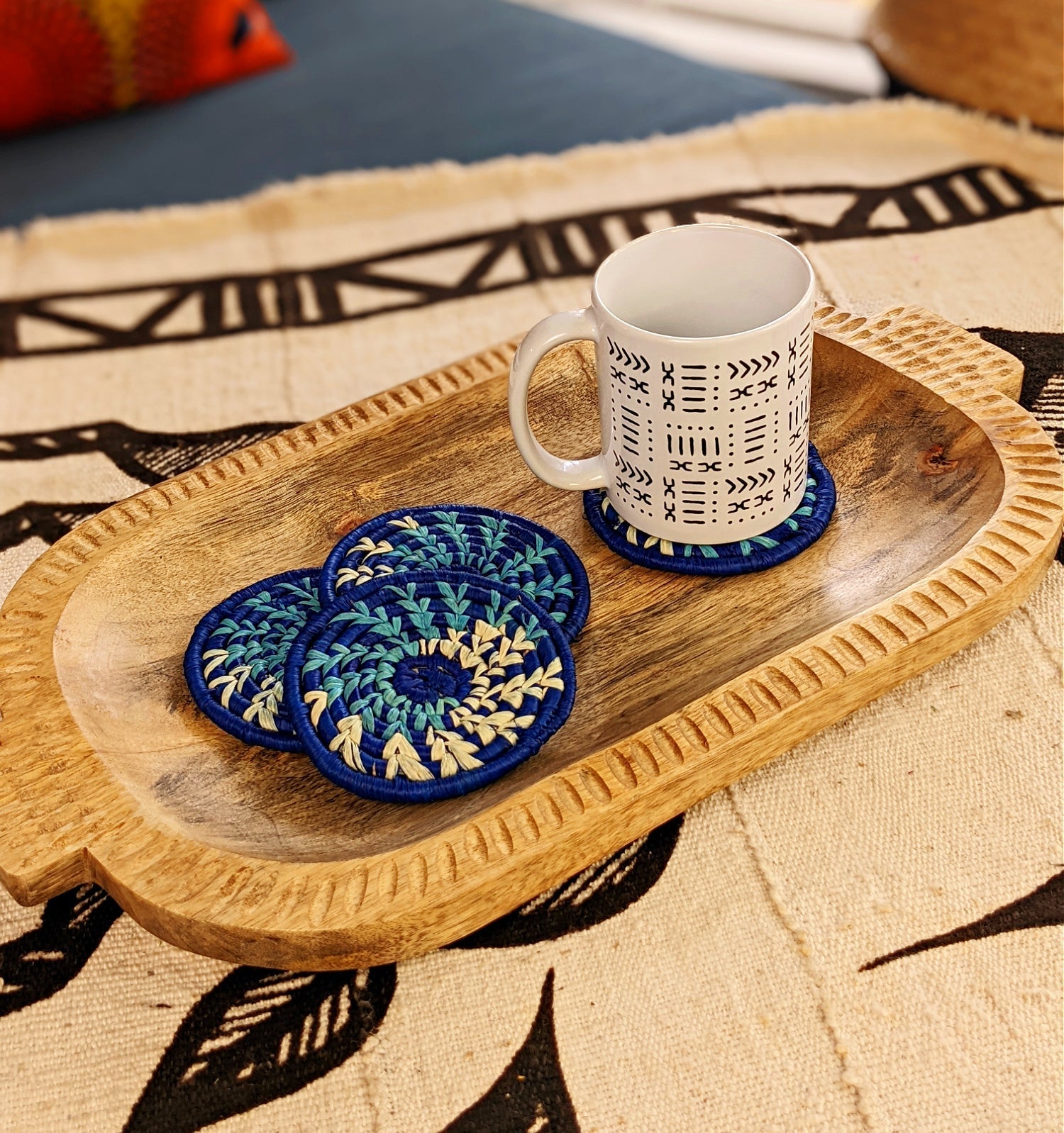 Handmade woven drink coasters set of 4 by Reflektion Design in various colors, featuring intricate textured patterns on a wooden table.