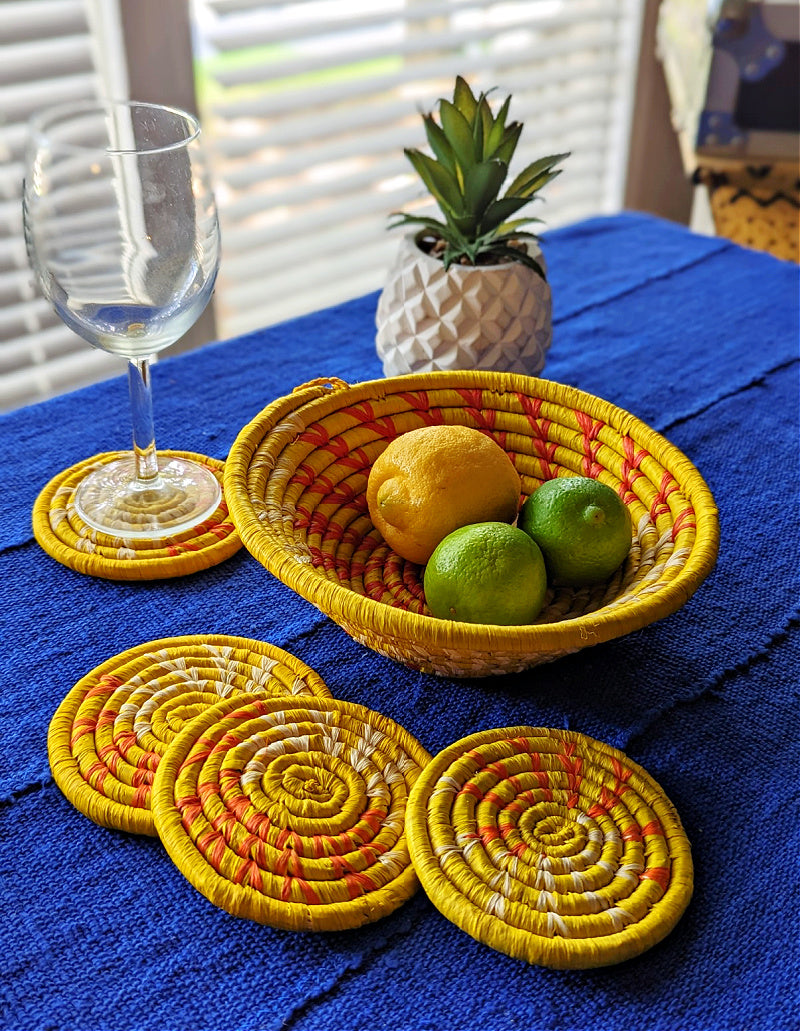 Small woven Raffia African baskets in multiple colors on a blue tablecloth, used as boho-style African table decor.