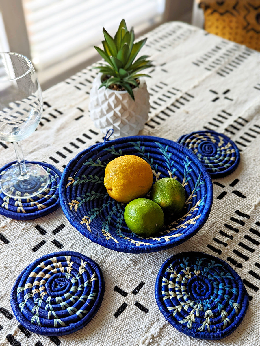 Set of four handmade woven drink coasters in blue, designed by Reflektion Design, featuring colorful African-inspired patterns.