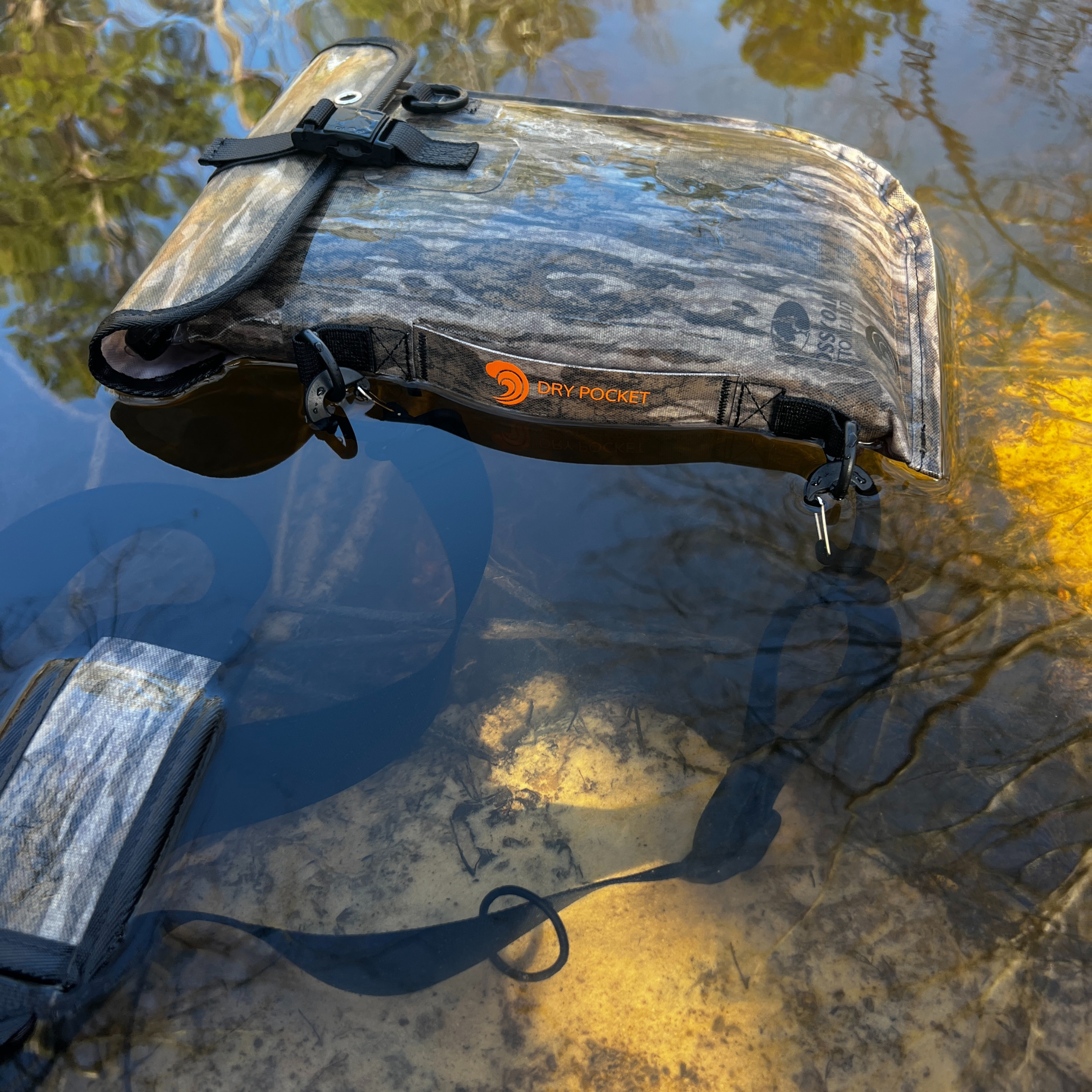 Auto-sealing waterproof floating pistol bag by Dry Pocket, showing the bottomland camouflage exterior and secure seal design.