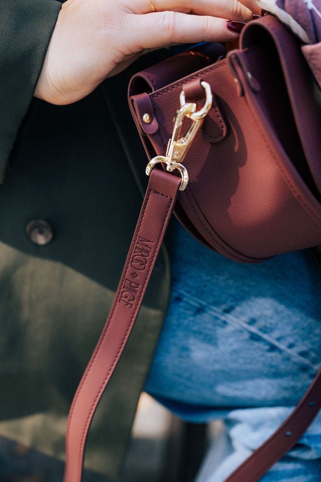 Burgundy semi-circle Margo Paige handbag with adjustable strap and gold-tone hardware, stylish crossbody bag for daily use.