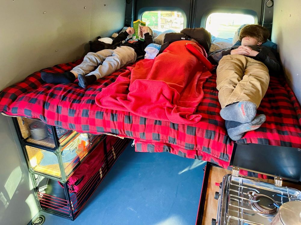 Mercedes Sprinter 170 camper van conversion DIY kit by TNTvans, featuring a cozy bed setup inside the camper van.
