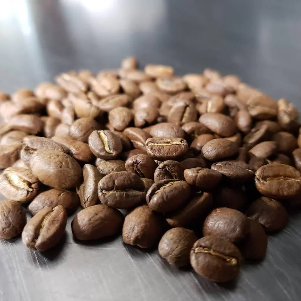 Cast Iron™ medium roast coffee from Iron Bean Coffee Company in a textured bag with rich, dark coffee beans visible.