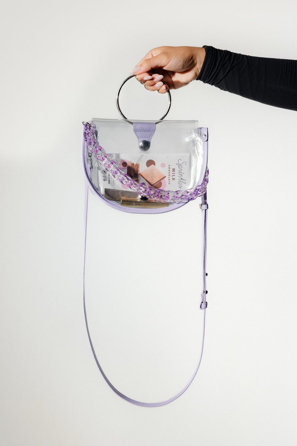 Clear semi-circle crossbody handbag by Margo Paige with a sleek, transparent design and adjustable strap, perfect for everyday use.
