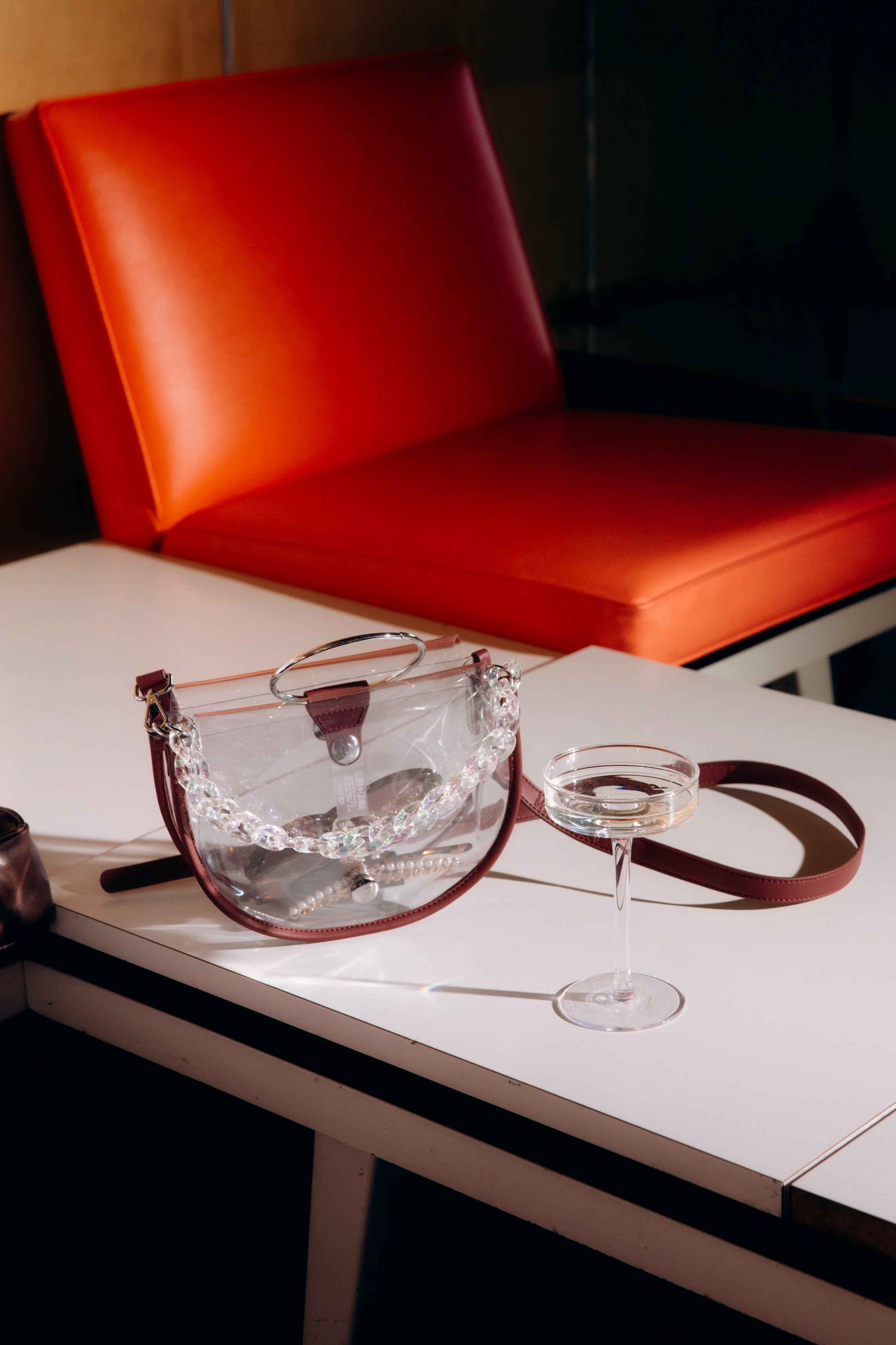 Clear semi-circle crossbody handbag by Margo Paige with a sleek transparent design and minimalist style.