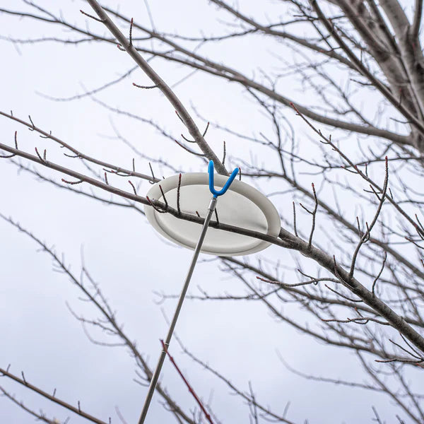 In The Bag Disc Golf Company Disc Retriever accessory hanging from a tree branch, designed for retrieving discs from difficult spots.