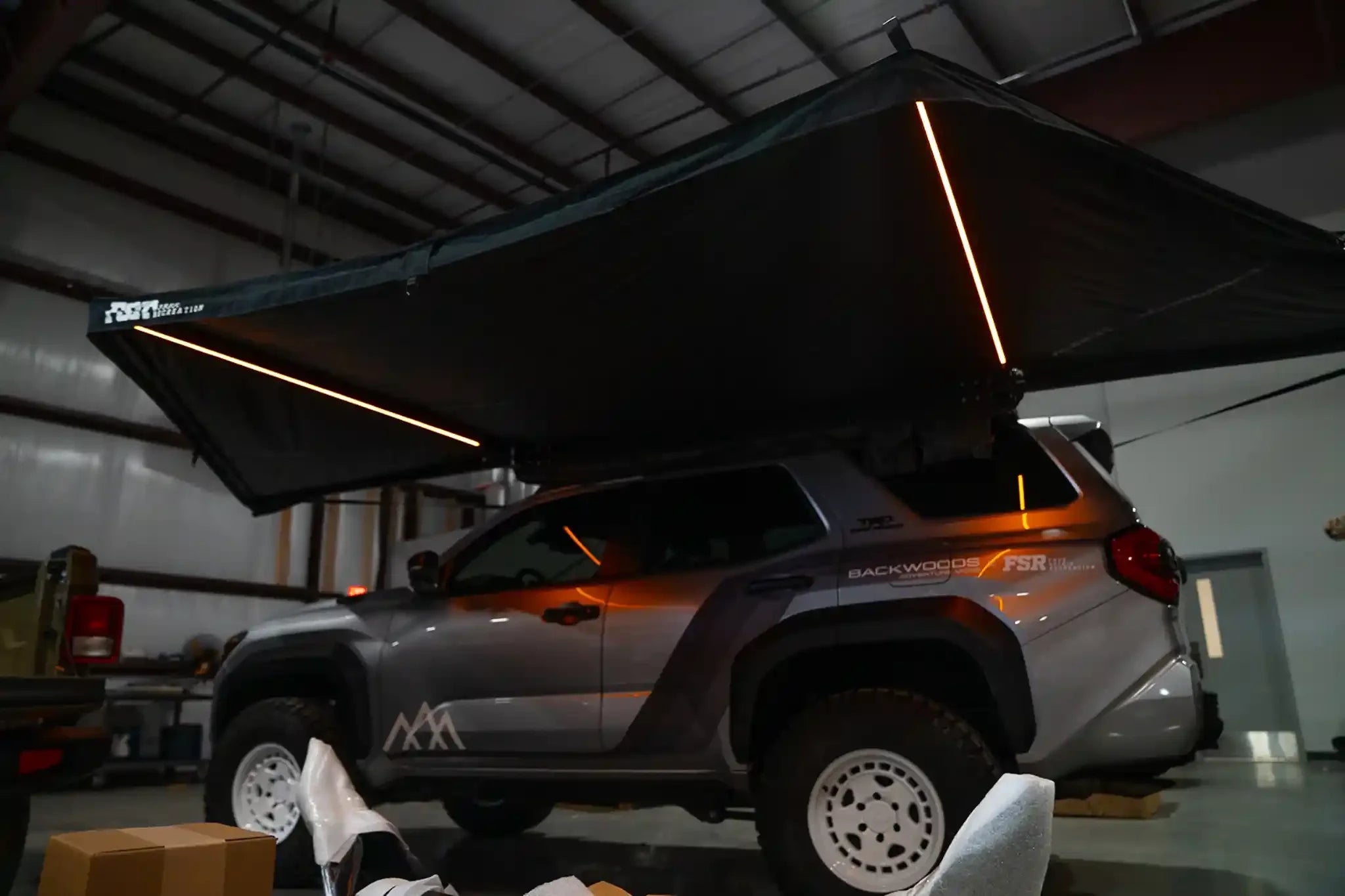 Freespirit Recreation 180 Awning V2 with amber LED lights, outdoor camping awning setup with fabric and lighting on the vehicle side.