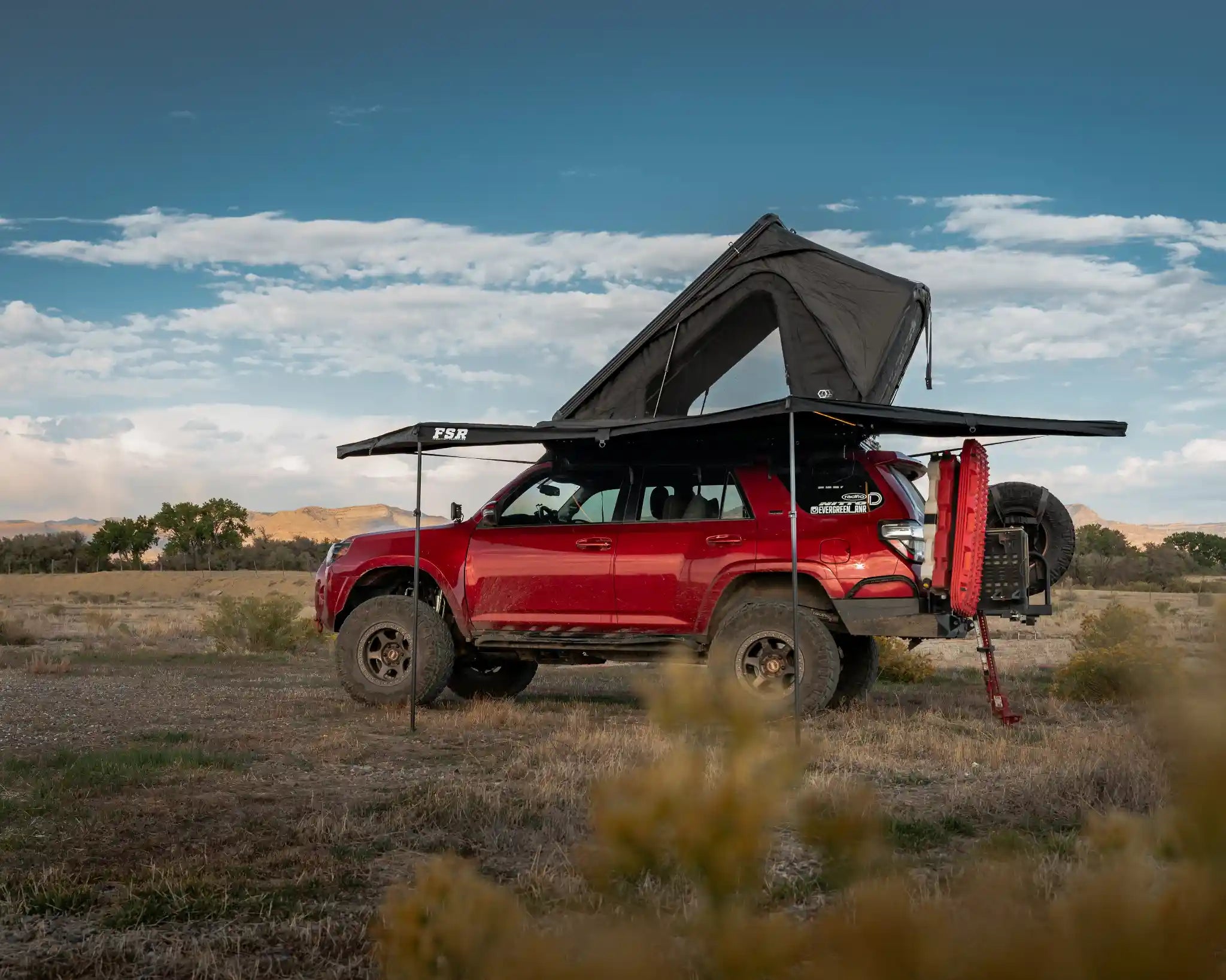 Freespirit Recreation 180 Awning V2 attached to a red 4Runner SUV, providing shade and shelter outdoors.