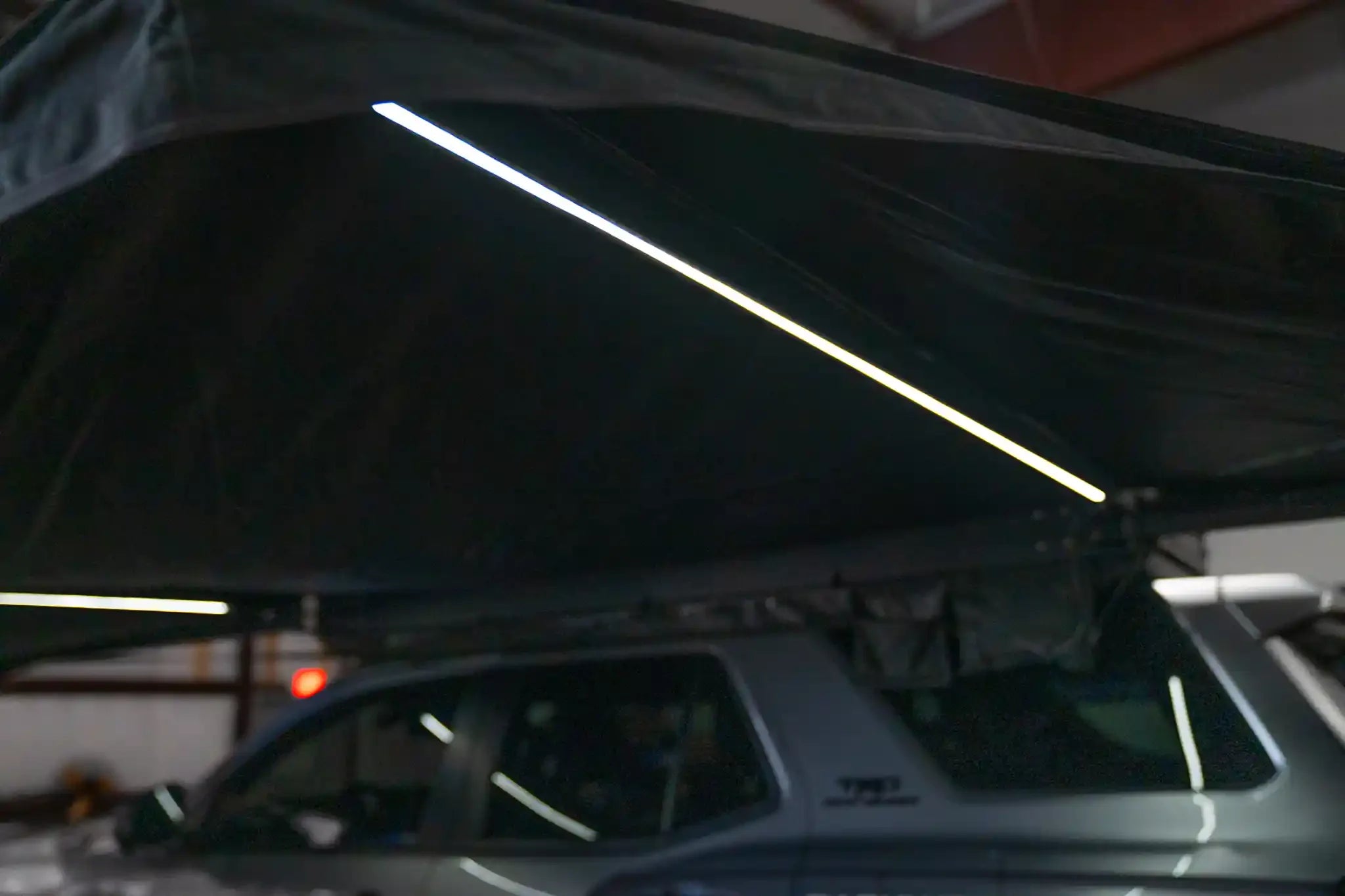 White 180 Awning V2 from Freespirit Recreation with integrated LED lights, fully extended showing its outdoor camping setup.