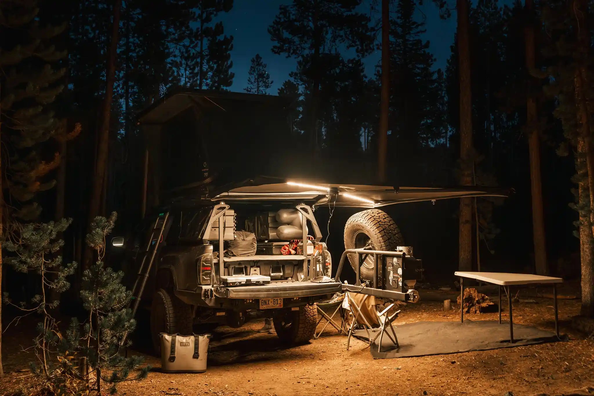 Freespirit Recreation 270 Awning V2 deployed outdoors with integrated lights on, providing shade and shelter for camping.