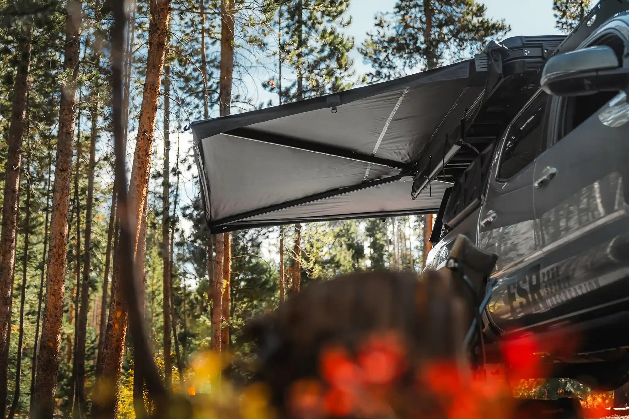 Freespirit Recreation 270 Awning V2 deployed outdoors, providing shade with durable fabric and support arms on an overland vehicle.