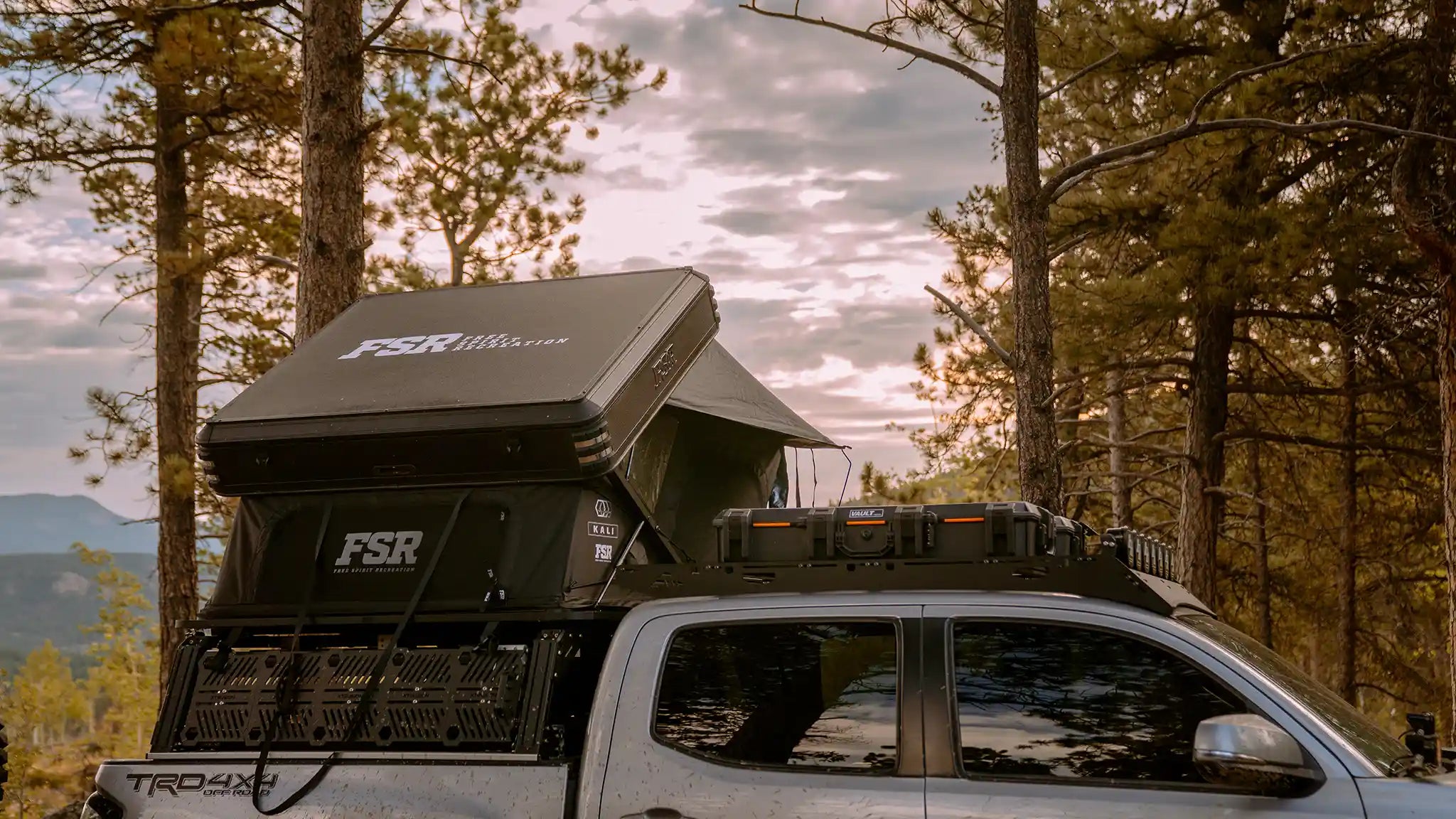 Freespirit Recreation Kali rooftop tent mounted on overland bed rack, open for camping with fabric sides and ladder.