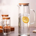 Hand-blown glass pitcher and cups set with bamboo accents by Tea + Linen, showcasing elegant, artisanal drinkware.